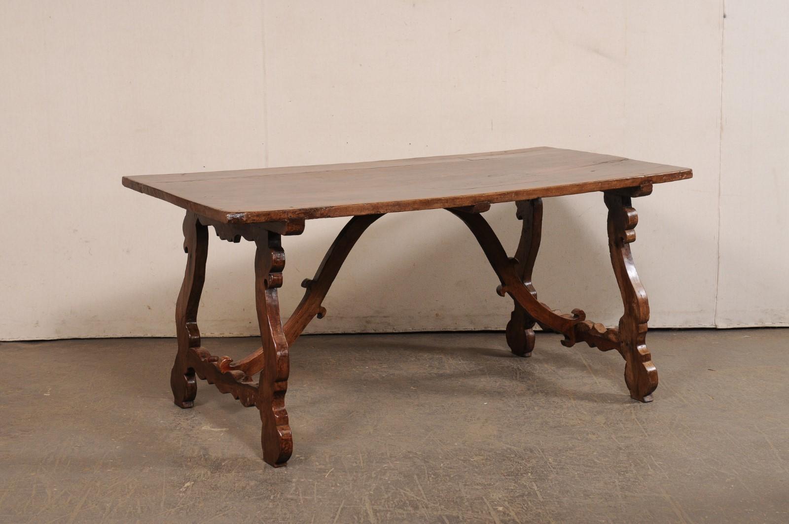 Table de salle à manger italienne en bois sculpté, avec pieds en lyre et traverse en bois, du tournant des XVIIIe et XIXe siècles. Cette table ancienne d'Italie a un plateau de forme rectangulaire, reposant sur une paire de pieds tréteaux sculptés