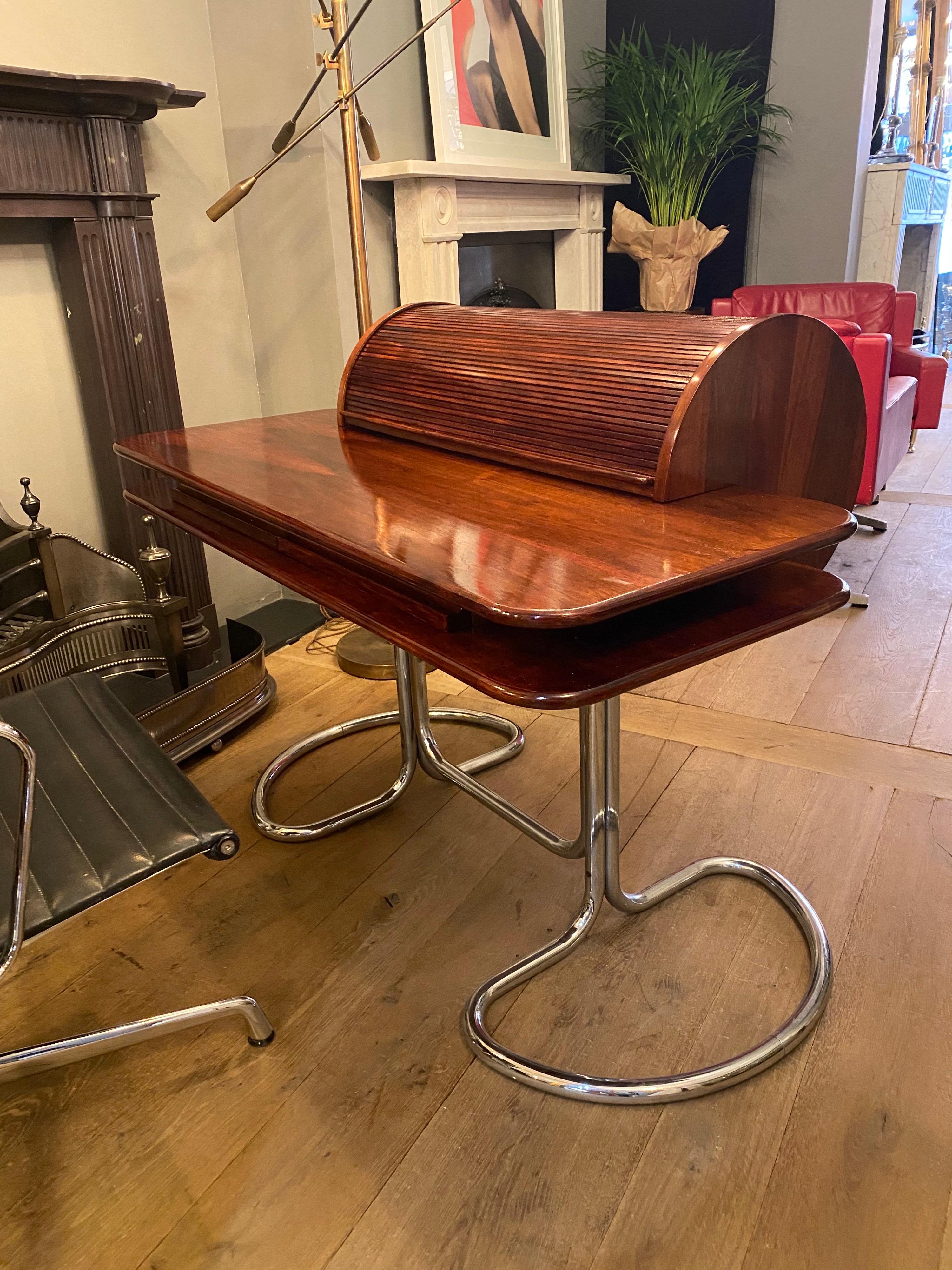 A superb example of this Iconic Italian desk manufactured by Bernini and designed by Giotto Stoppino.
Supported on tubular chromed legs, the rich wood top with rolling tambour, which reveals the original trays for stationary. Two discreet drawers