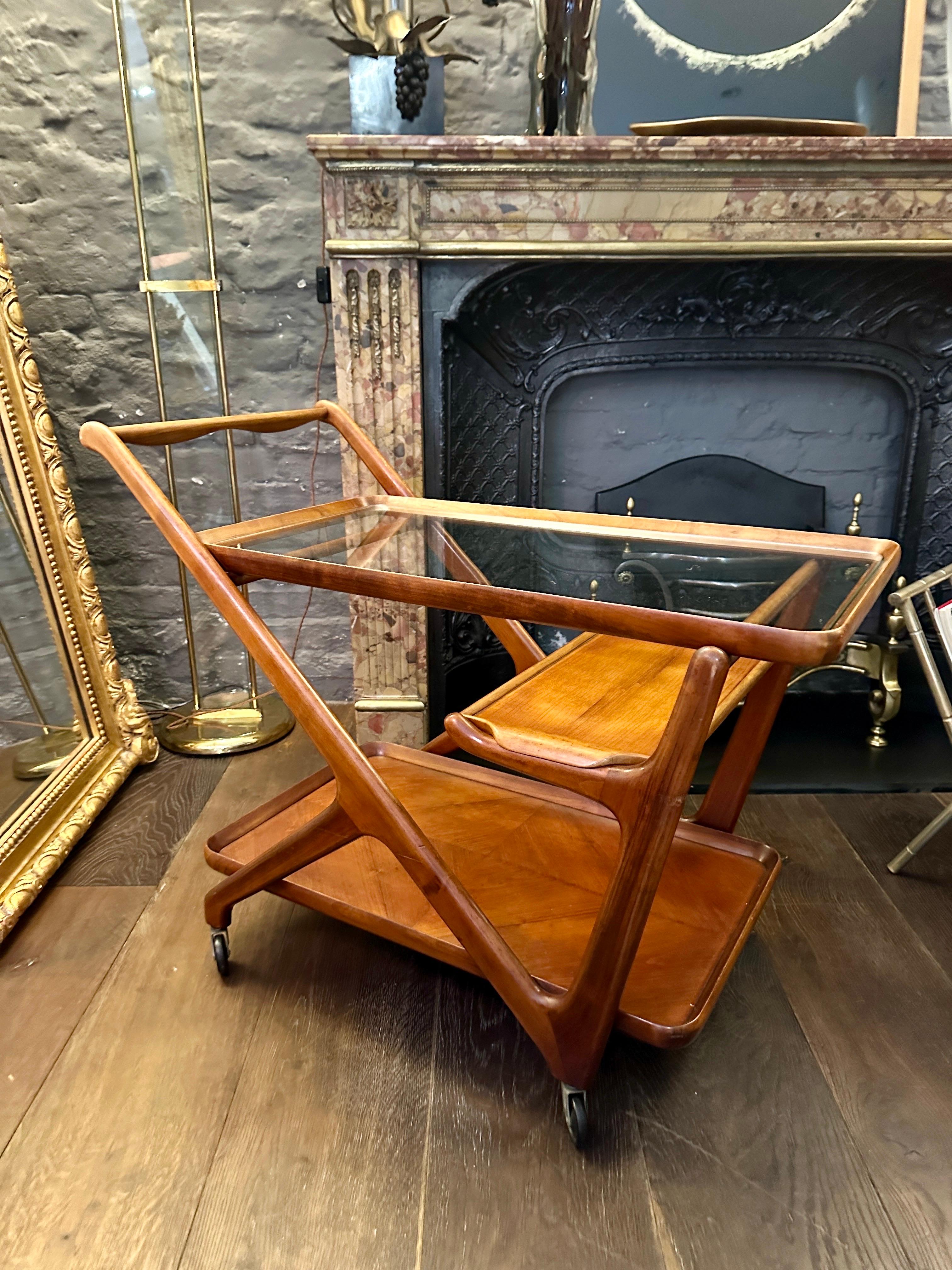 An Italian Mid century Bar cart or trolly made in Walnut, with clear glass top and polished walnut parquet bottom. Its original tray still in place and supported on steel castors.

Cesare lacca is appreciated for his contribution to Italian Design