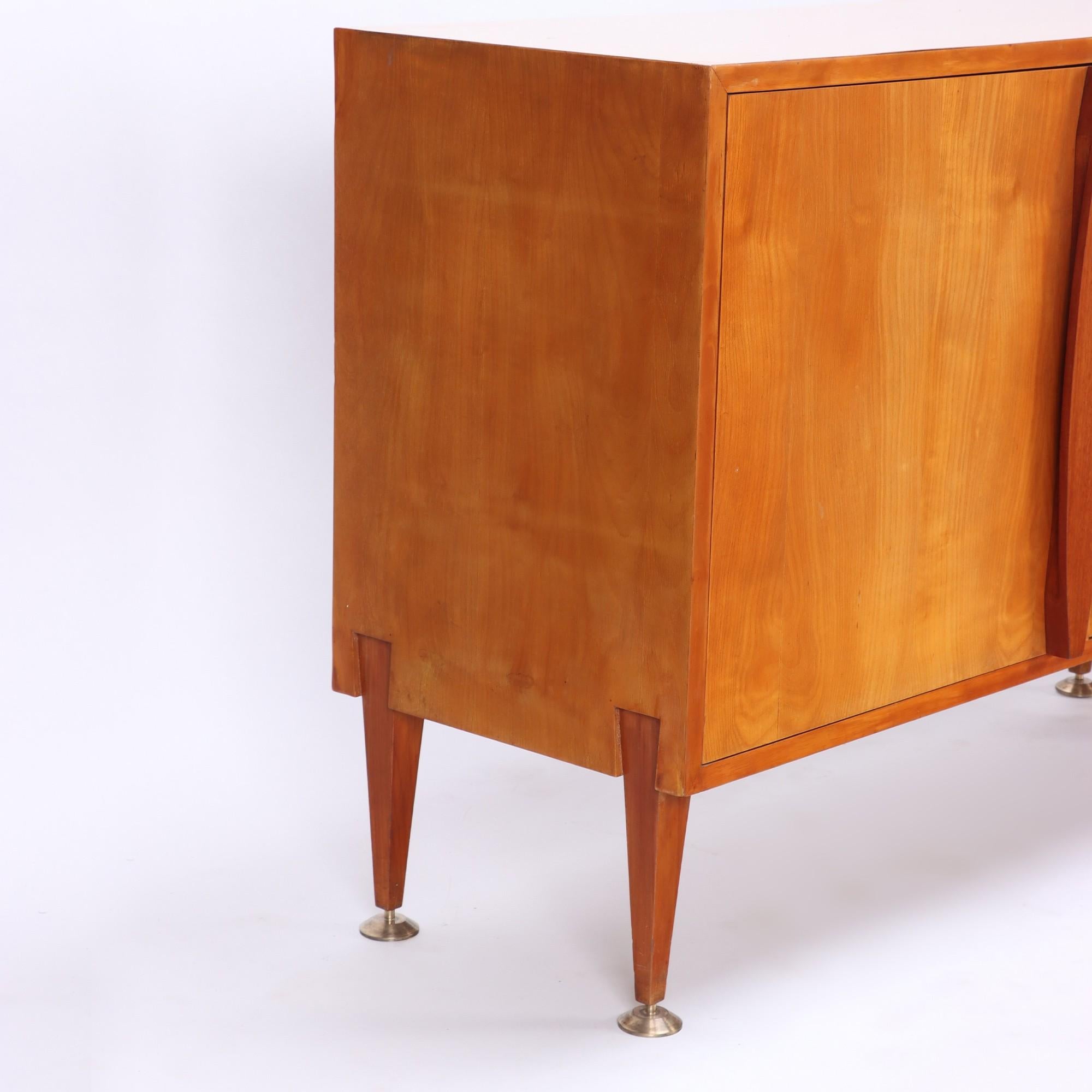 A beautifully designed Italian Mid-Century Modern 2 tone sideboard, comprising of four drawers with detailed wooden handles flanked by two sliding doors and side door which open to shelves. Brass details on all six legs . Circa 1960.