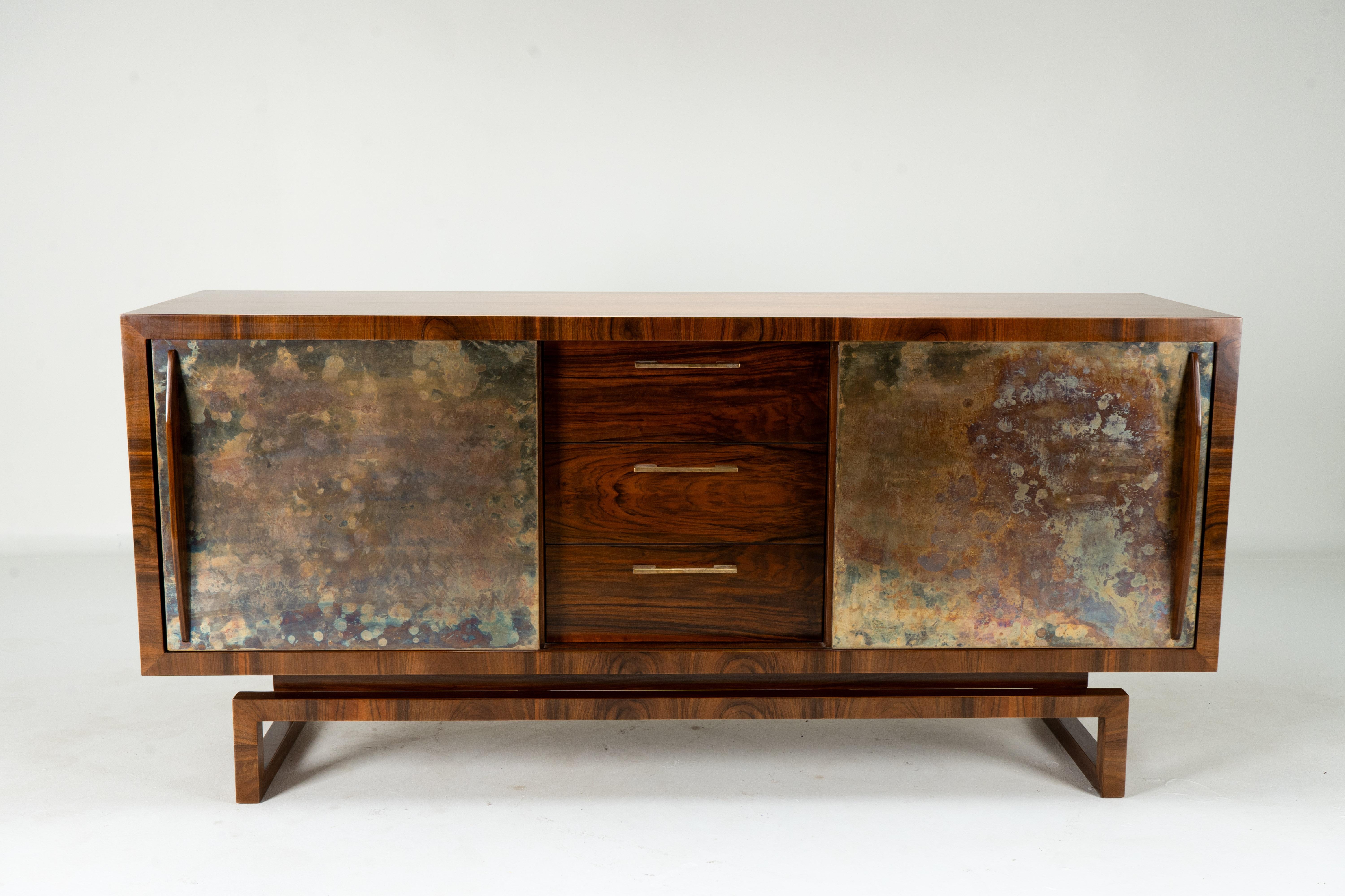 This Italian sideboard dates to the late 1940's or early 1950's and features classic Mid-Century Modern styling. The piece is crafted in walnut veneers with brass-sheathed doors. Unlike Art Deco designs that often used exotic imported hardwoods like