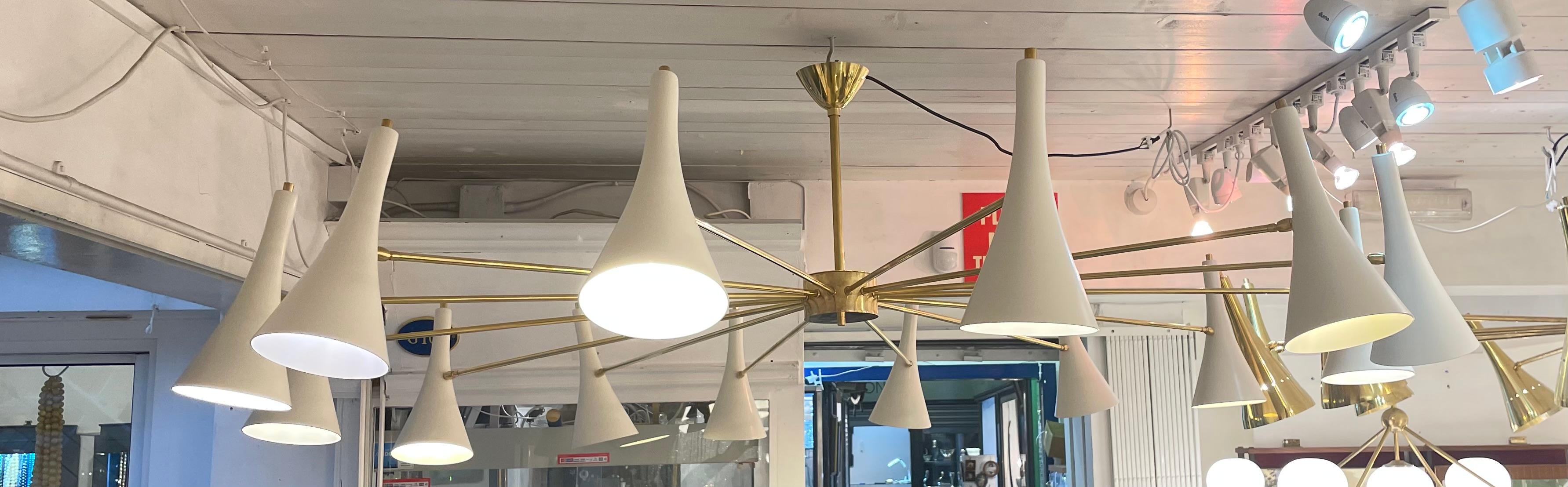 A stunning Italian modernist chandelier in brass with 14 arms and shades in ivory metal, circa 1970.