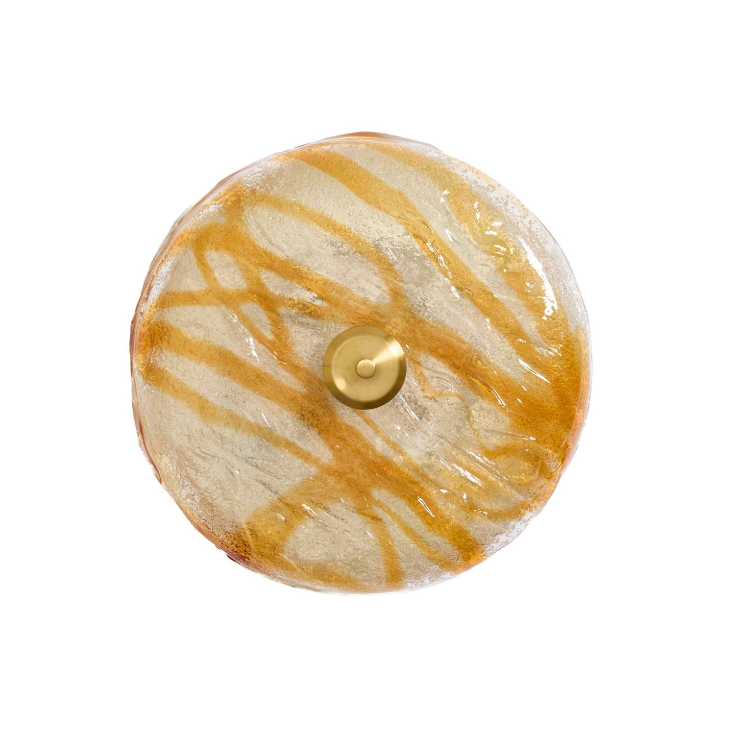 Una montatura da incasso in vetro fuso italiano di Murano. La superficie strutturata presenta striature di vetro color ambra, la parte superiore con bordo rialzato. L'apparecchio è fissato sul lato inferiore con una rosetta in ottone e un terminale.