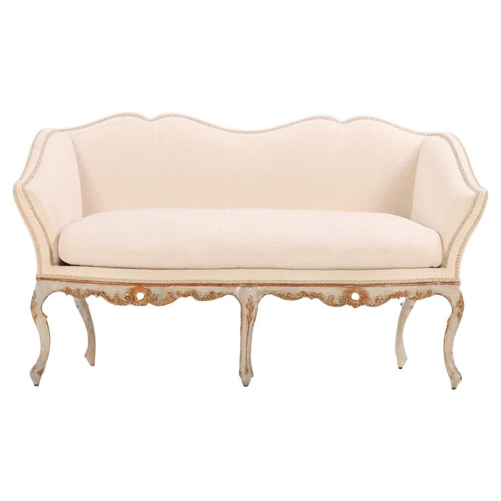 An Italian painted and carved settee, 18th C., in recent fabric. For Sale