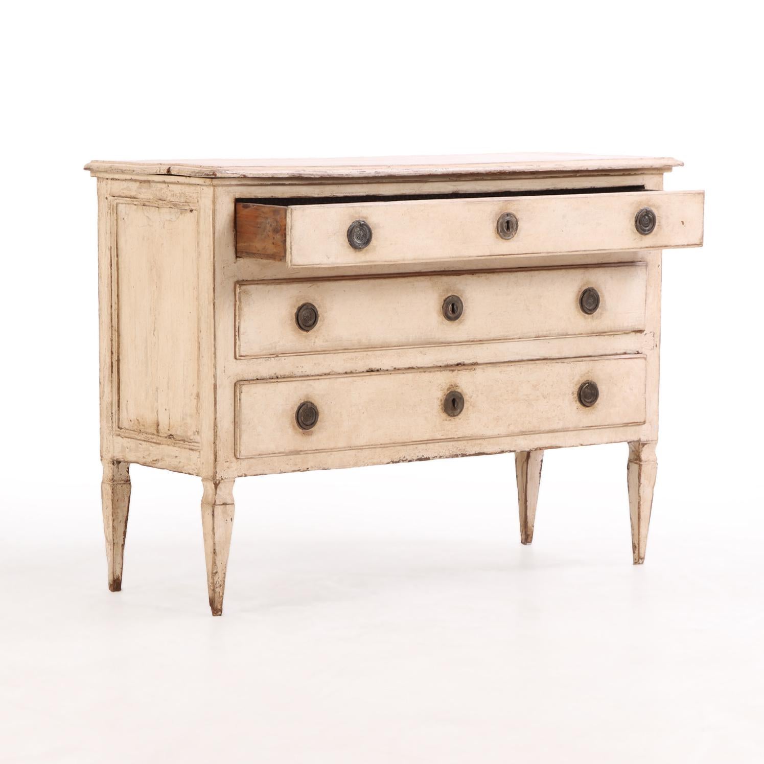Featuring three long drawers with simple yet refined hardware, the case is accented with paneled ends, enhancing its architectural presence. Raised on tapering square legs, the piece reflects a neoclassical influence with clean lines and a
