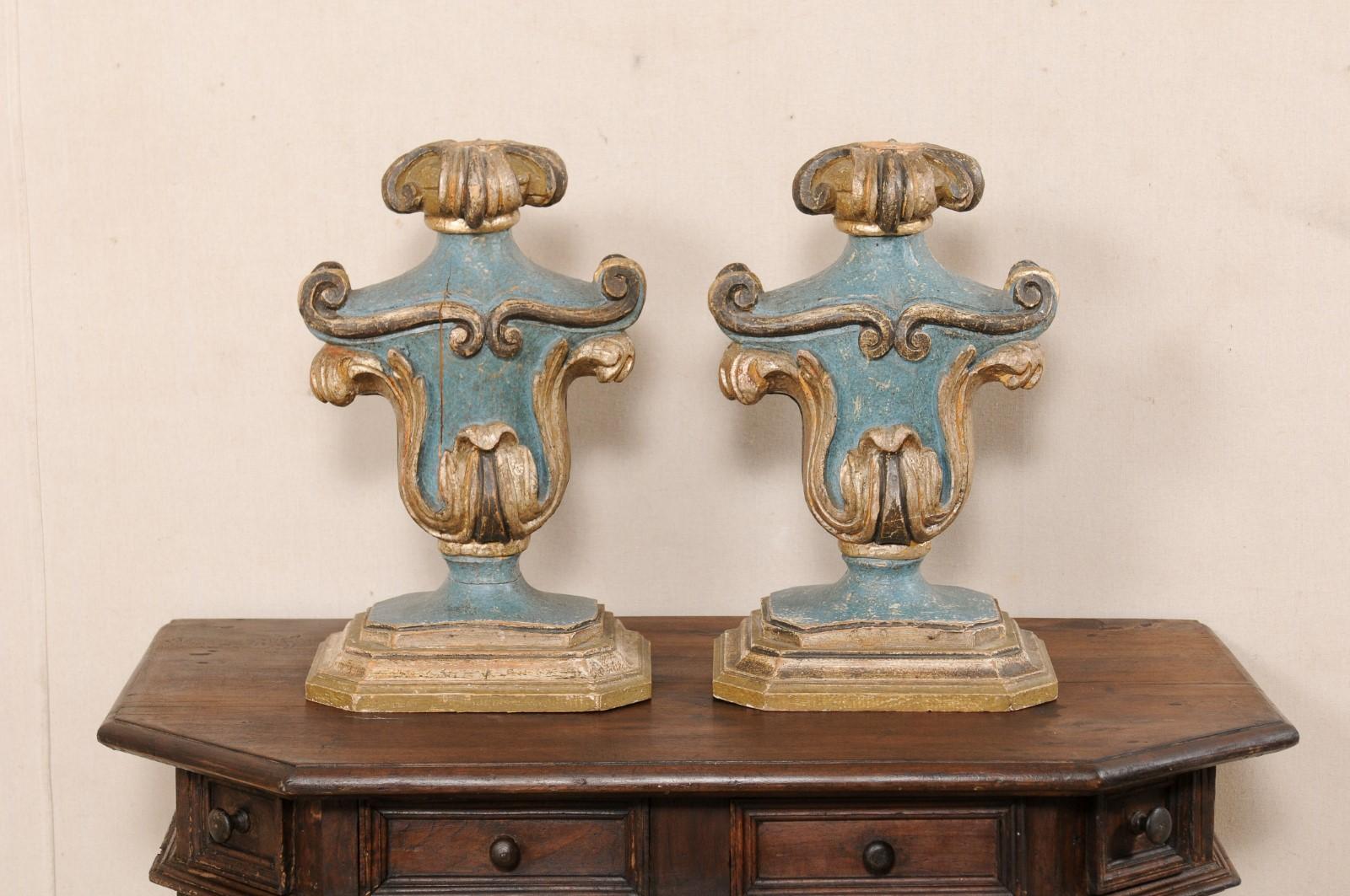 An Italian pair of carved and painted wood fragments. This vintage pair of table top decorations from Italy once had prickets and were used as candle sticks, but now repurposed as great decorative accessories. The fragments each have an urn shaped
