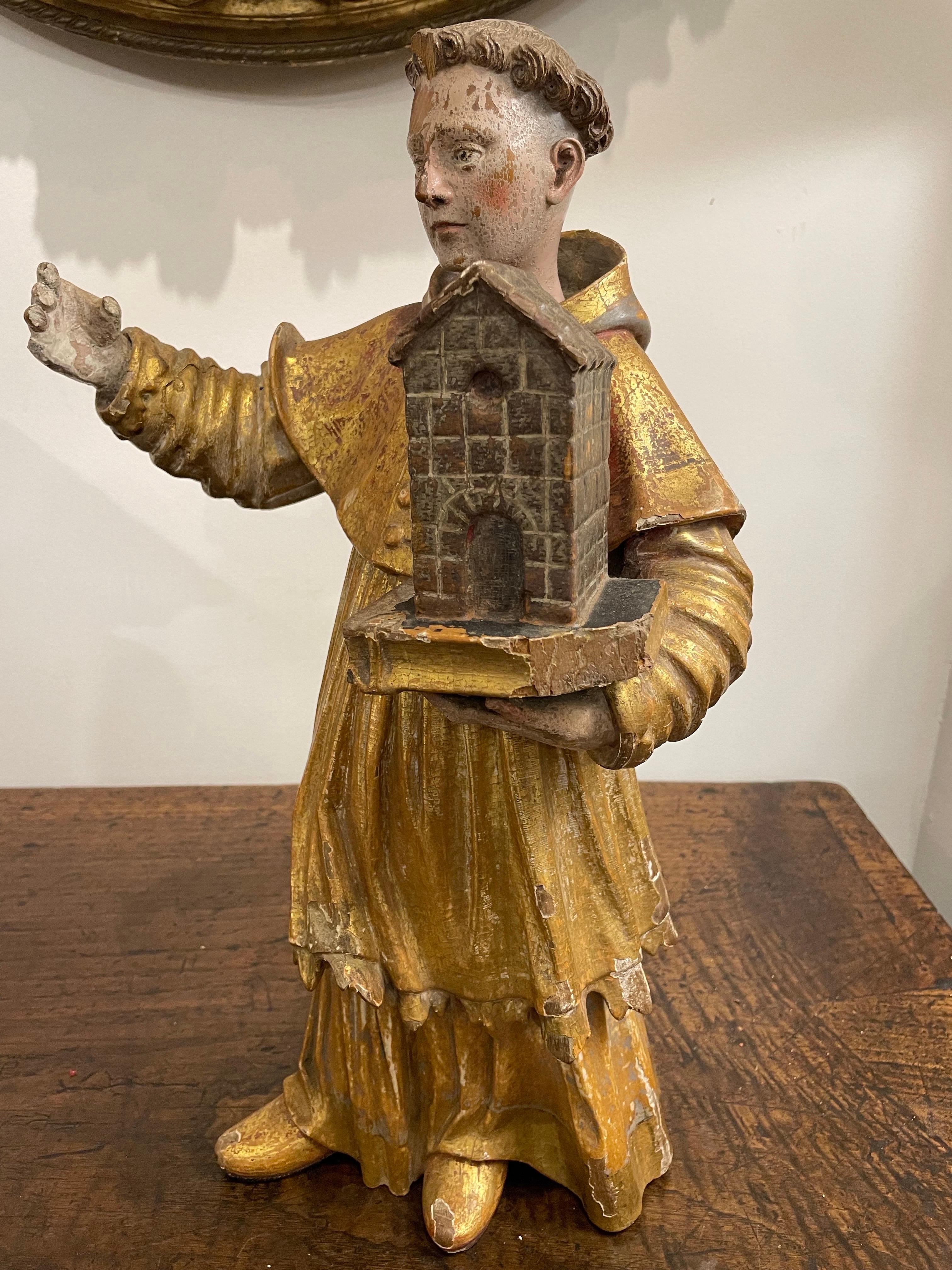 Figura policromada italiana de un santo, siglo XVIII

Procedencia:  
Colección privada de Australia Occidental.

Descripción:
Ataviado con una vestidura dorada de doble faldón, el personaje sostiene en la mano izquierda una pequeña maqueta de una