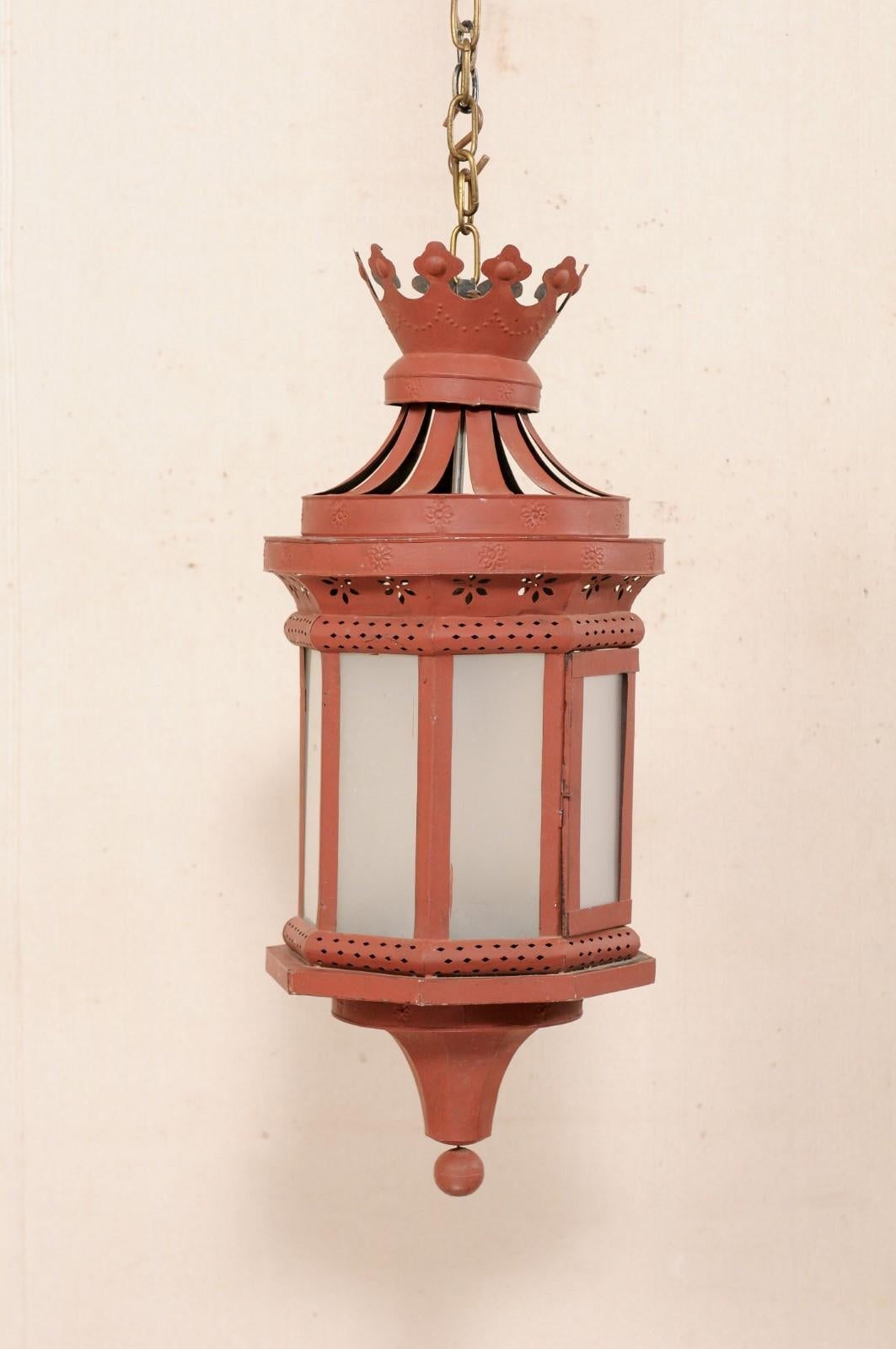An Italian red tôle lantern from the early 20th century. This antique lantern from Italy has a cut crown adorning its top, adorn with embossed swags and florals, with lantern beneath decorated with pierced cut-outs in a petite diamond and flower