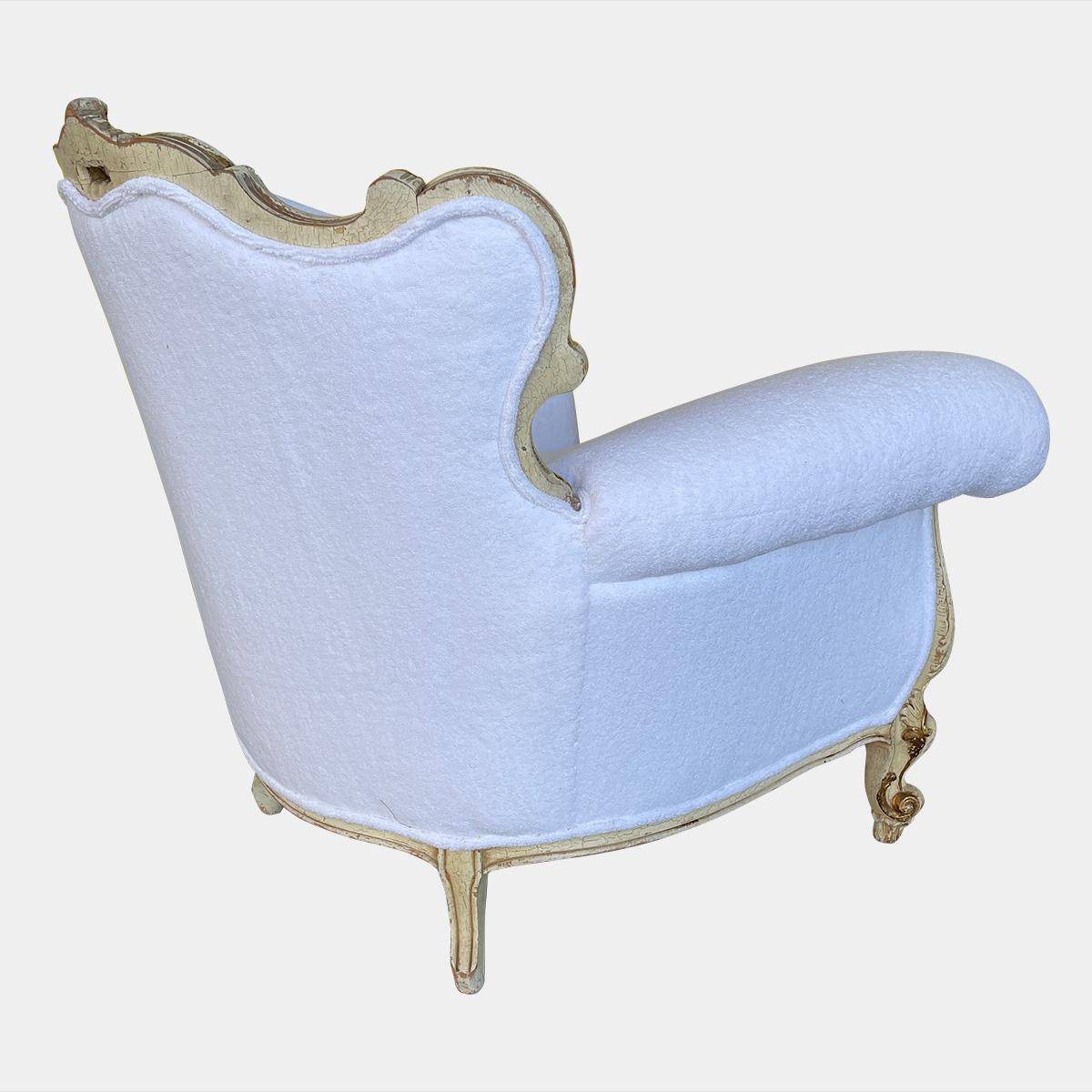 Grand fauteuil de style rococo de la fin du XIXe siècle, recouvert de Whiting blanc et doté d'un coussin à plumes. Le cadre doré du colis est orné de rinceaux, de feuillages et de coquillages, avec une patine d'origine et des traces de choc. Re