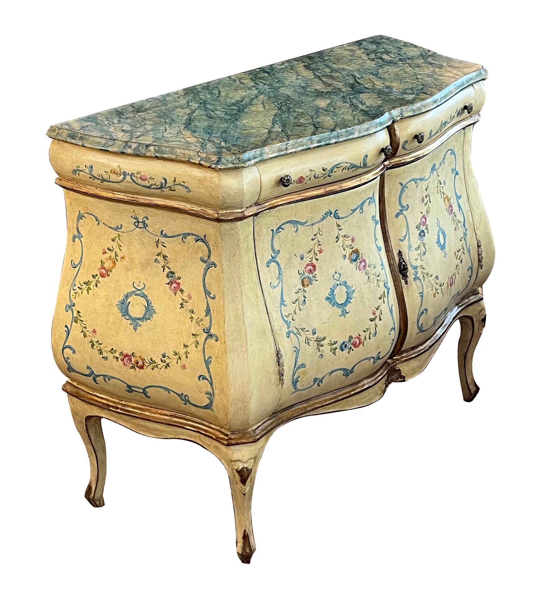 the shaped faux marble top above a bombe-form case fitted with 2 drawers over 2 doors all raised on cabriole legs; the whole painted with foliate vines and floral garlands on a muted butter-yellow ground.