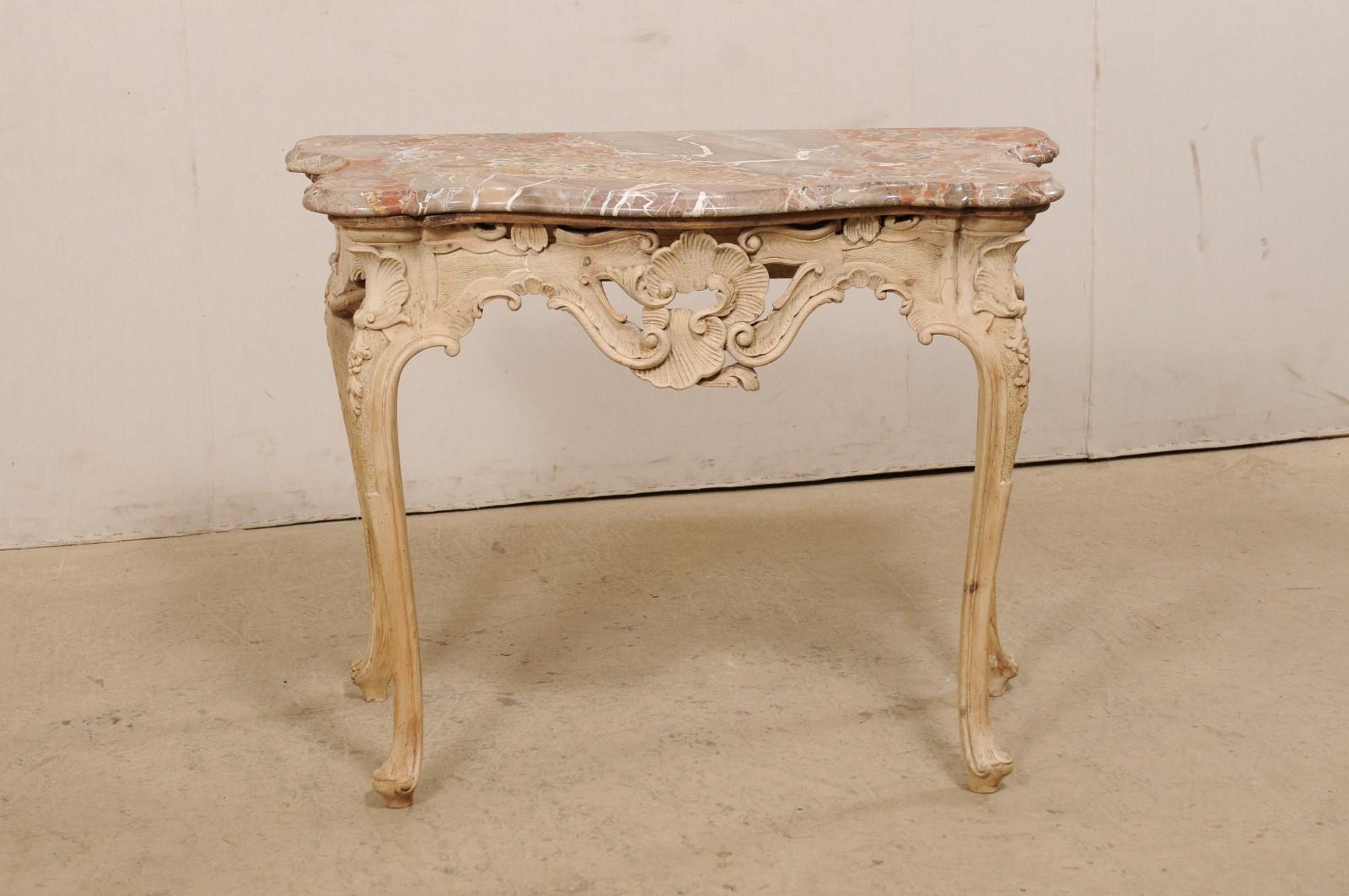 An Italian console table with it's original marble top from the mid-20th century. This vintage table from Italy retains it's original marble top, which is flat across the backside (to allow the piece to rest comfortably against the wall) and nice,