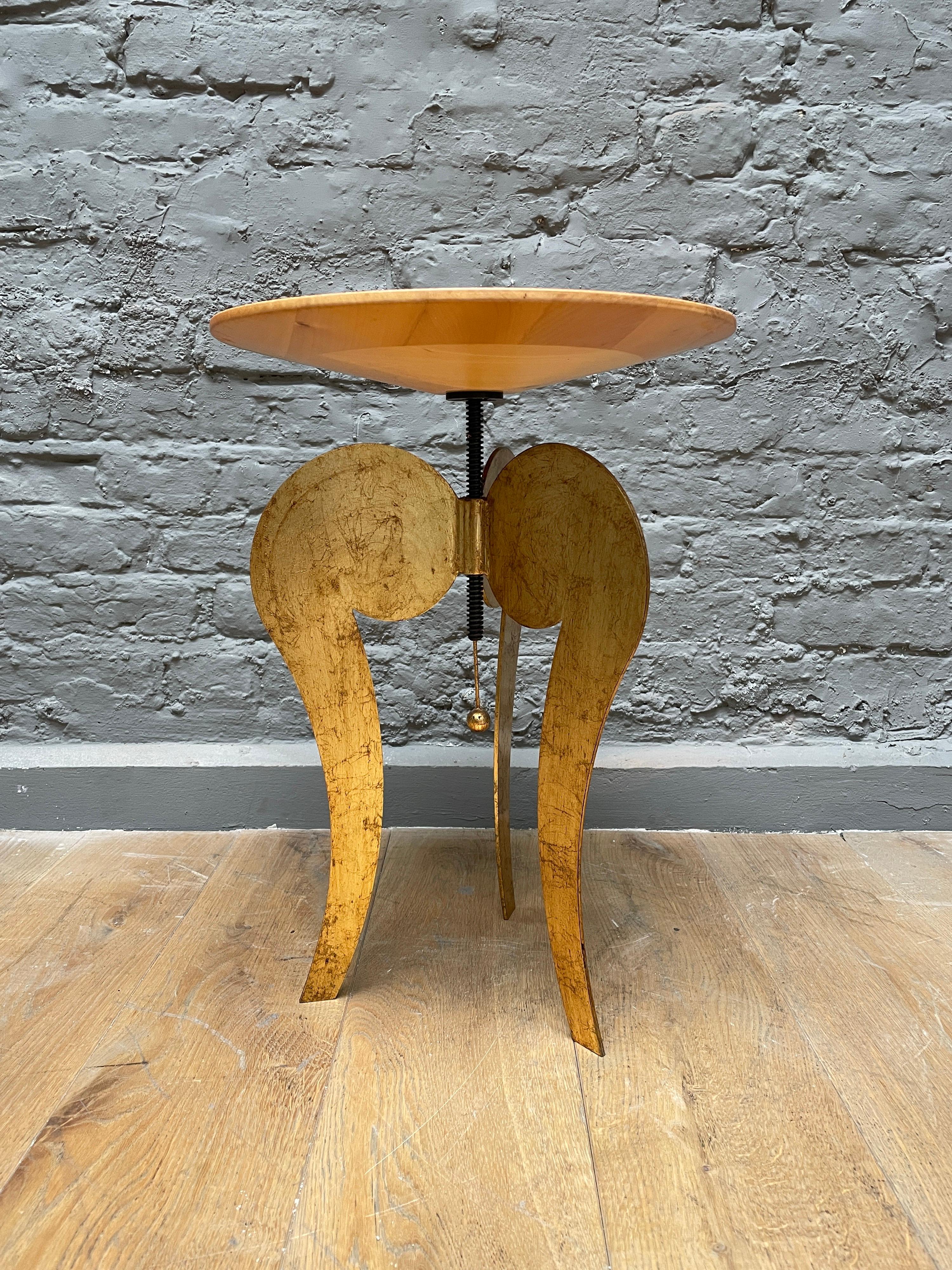 A late 20th century design, by Italian Sergio Terzani circa 1985. The table has blond wood top with a worked finish and gilt iron stylised tripod legs. The top can be adjusted in height. A smart usable table. 

Full height is 64cm.