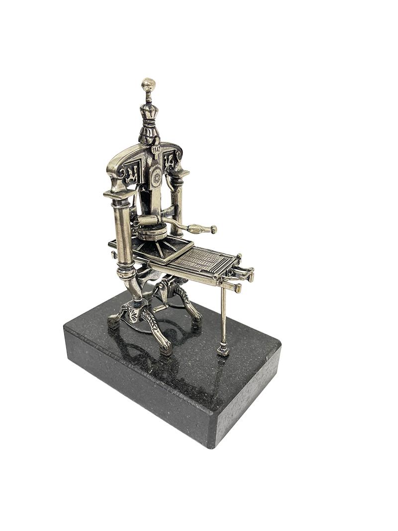 An Italian silver miniature printing press by Menegatti Brothers.

A silver miniature printing press on a marble base, after an example of a printing press from the 19th century. Made by the Menegatti brothers, Italy, worked during 1949- 2008