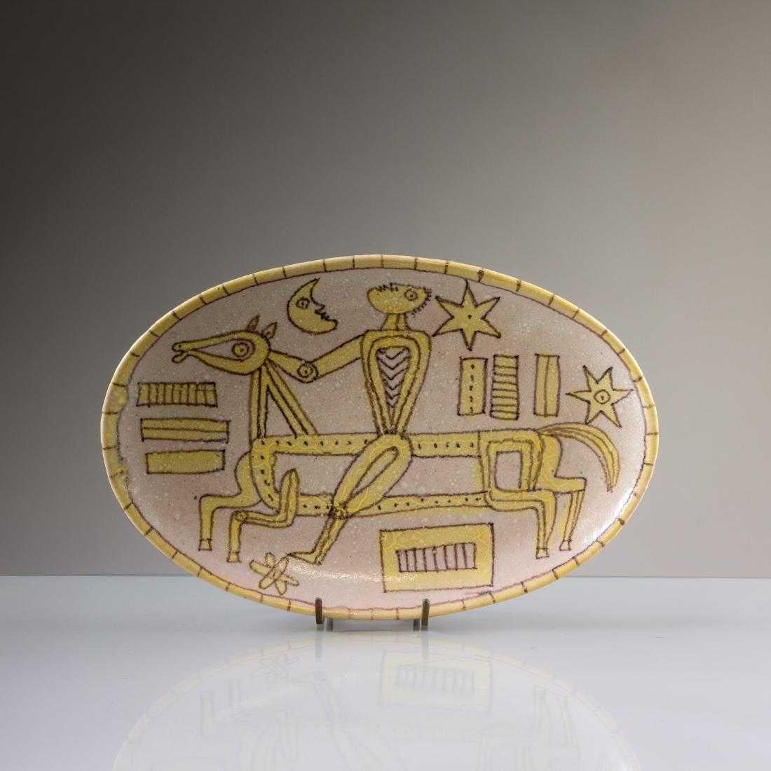 A large stoneware platter or charger in oval shape by Guido Gambon Italy circa 1960s. Beautifully covered in a white lava-like textured glaze and decorated with a yellow and black outlined figure riding a horse under the moon and the star. The