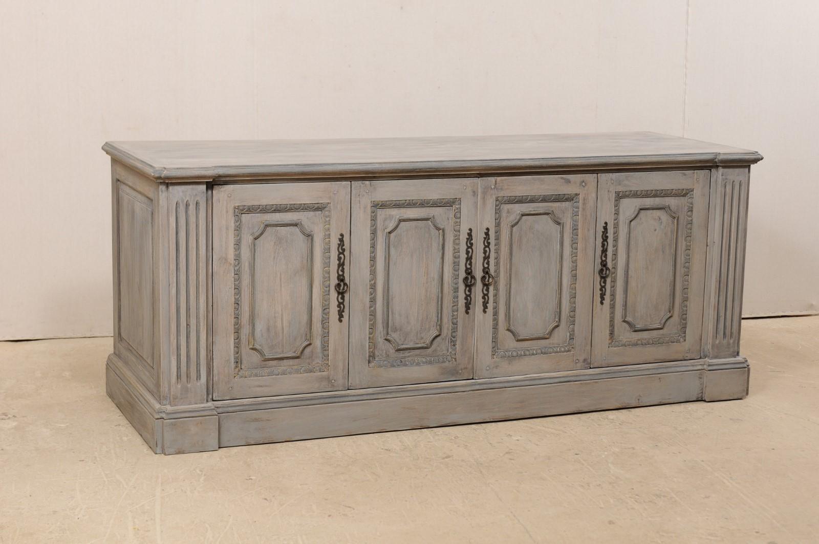 A vintage American painted wood buffet console cabinet. This vintage Italian style buffet cabinet, just over 7 feet in length, features four decorative recessed paneled doors, with egg and dart trim, set within fluted column-style side posts. The