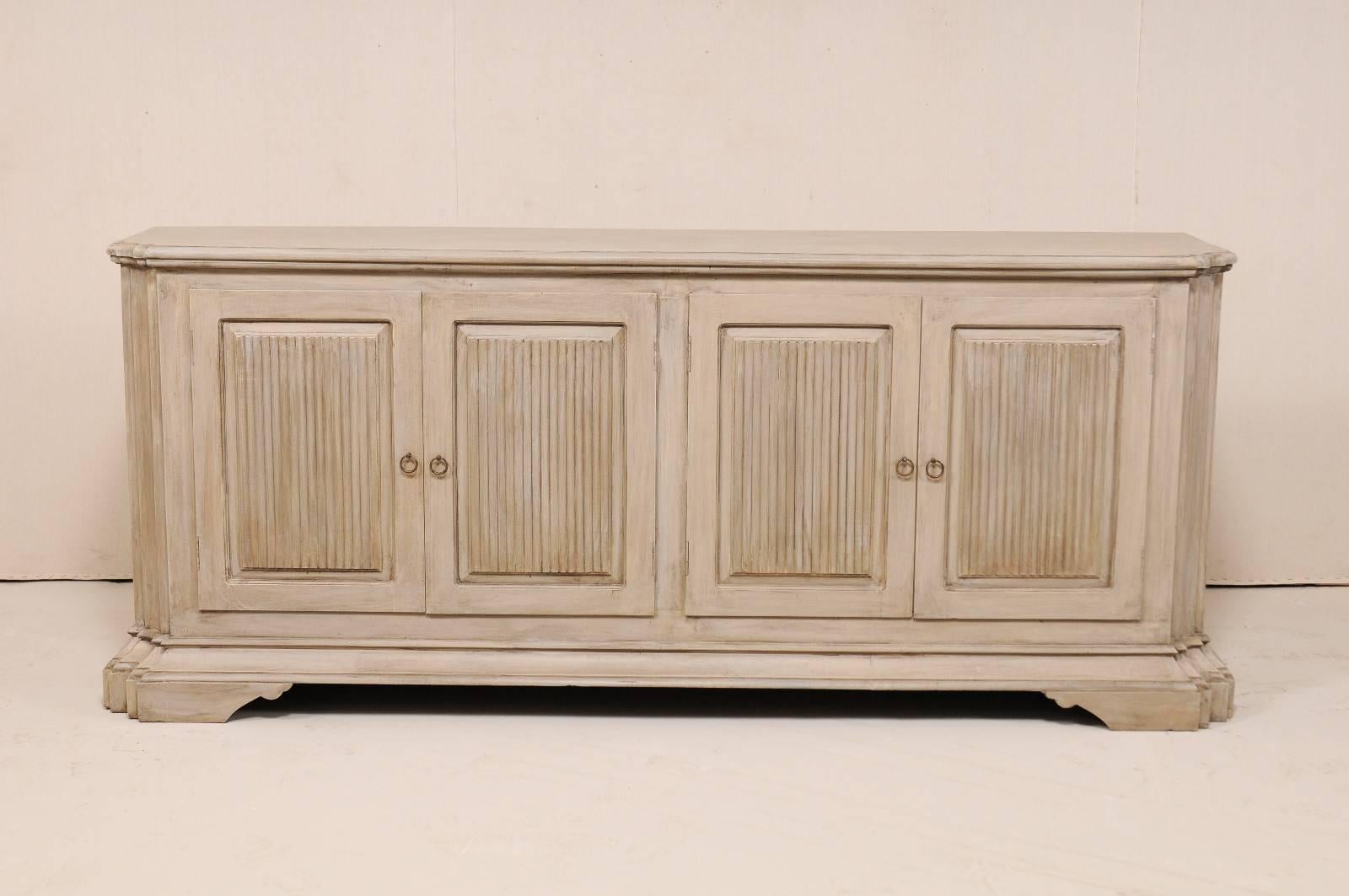 A vintage American painted wood buffet cabinet. This vintage Italian style custom buffet cabinet is over 8 feet in length and has been fashioned of old reclaimed doors and old wood. This cabinet features four reed paneled doors, nicely carved and