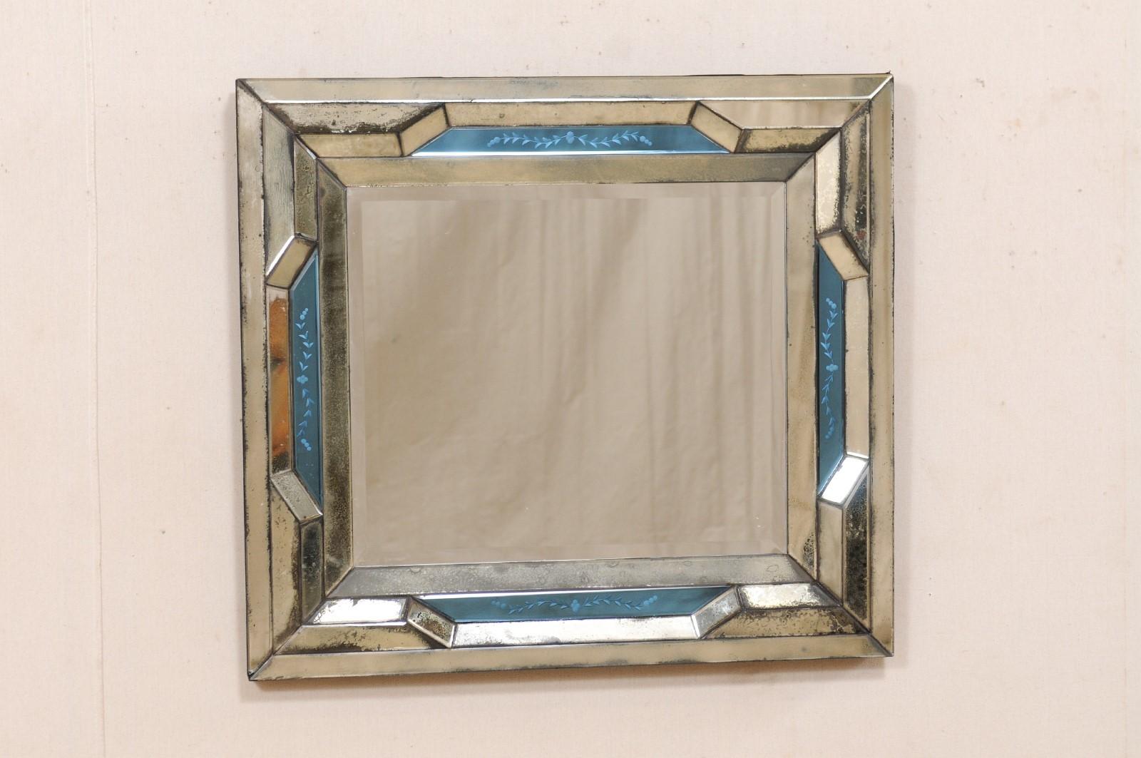 An Italian Venetian-style mirror with blue accents from the 20th century. This vintage mirror from Italy is near-square in shape and features a beveled center mirror, which is framed within a mirrored frame that has a heavier silvered/antiqued