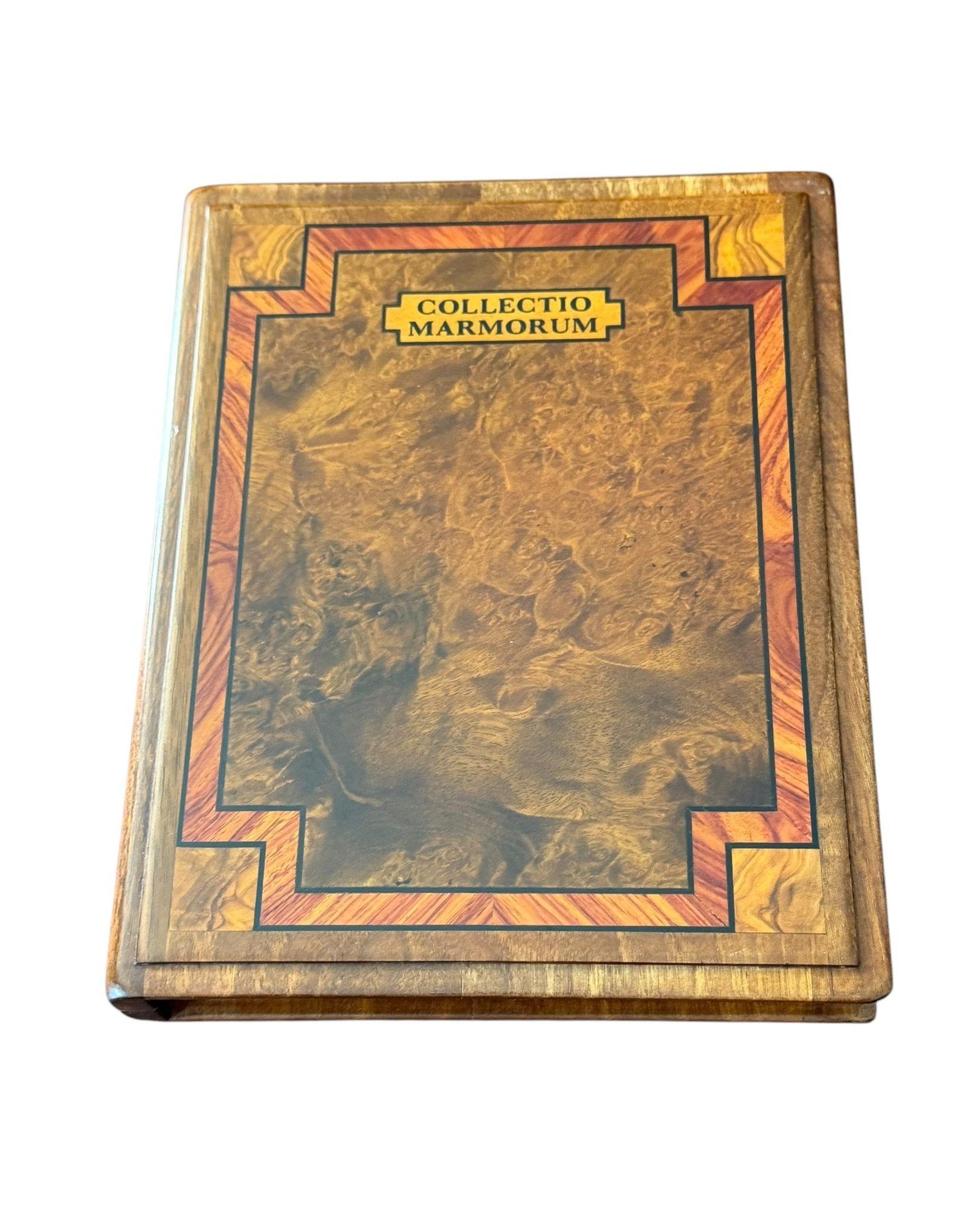 Il libro con cerniera in noce Burl intarsiato con legno di tulipano si apre per rivelare 18 varietà di biglie. Tra cui il porfido imperiale e il porfido verde,