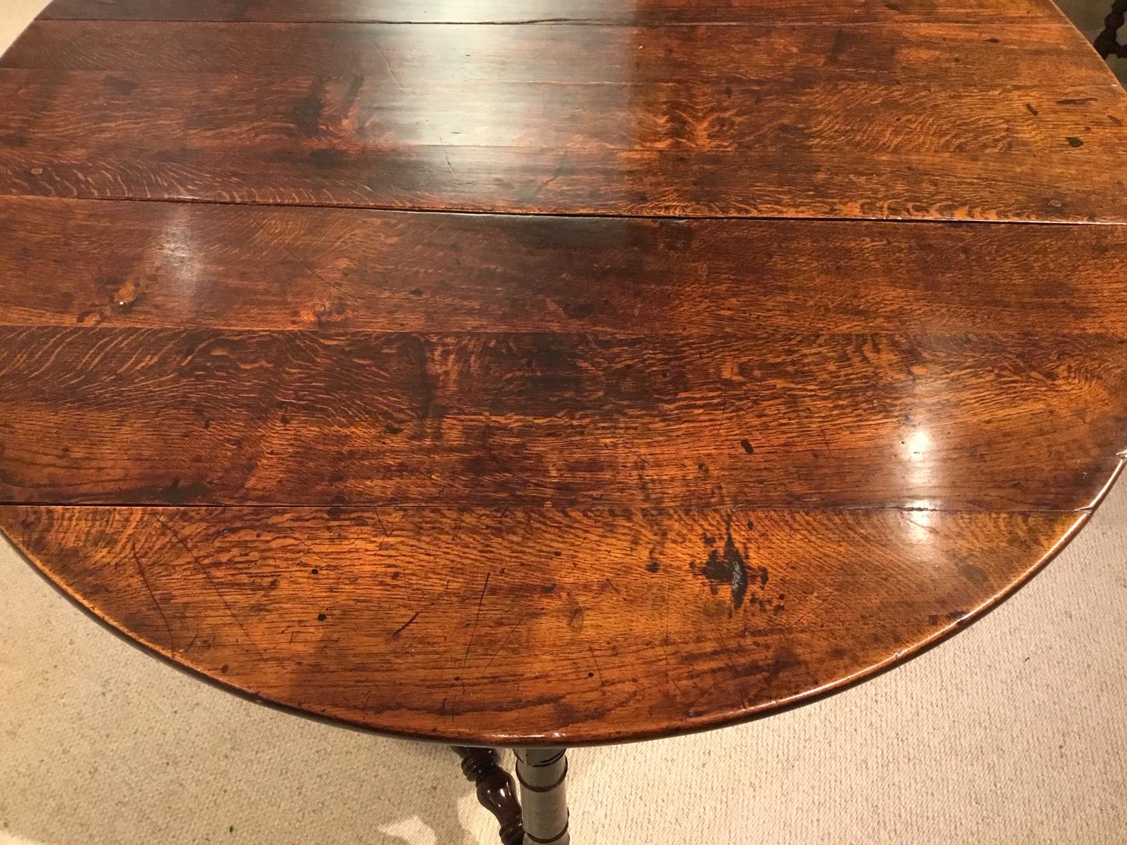 An oak 18th century period antique gate leg farmhouse table. The oval top of plank and pegged construction having twin drop leaves which open by means of a gate leg action. Supported on six turned supports united by bobbin turned stretchers of