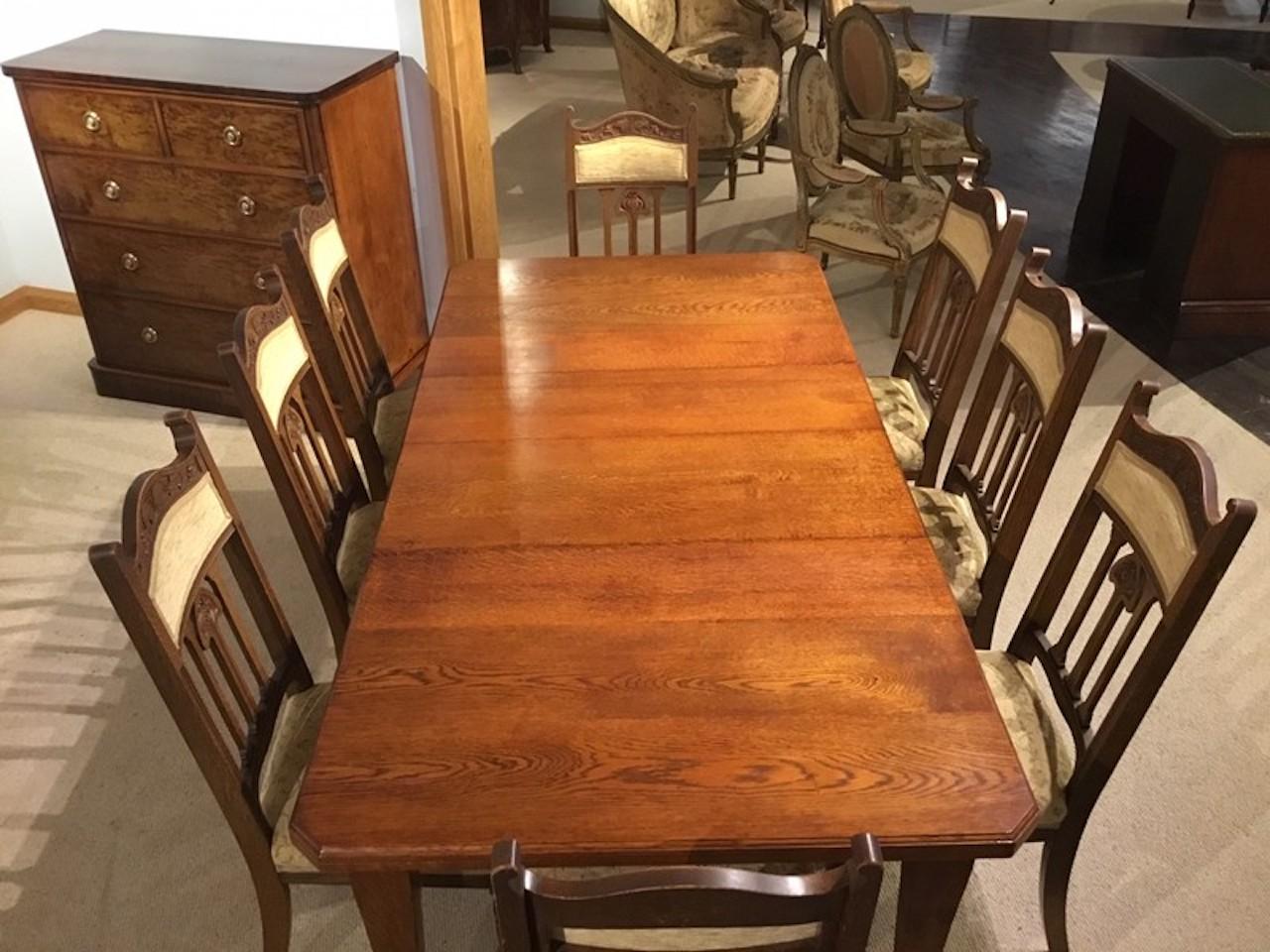 An oak Arts & Crafts Period extending dining table and 8 chairs. The table with a solid oak top with canted corners and two additional leaf inserts. This table is quite versatile and can be used to sit 4,6 or 8 people. Extending by winding mechanism
