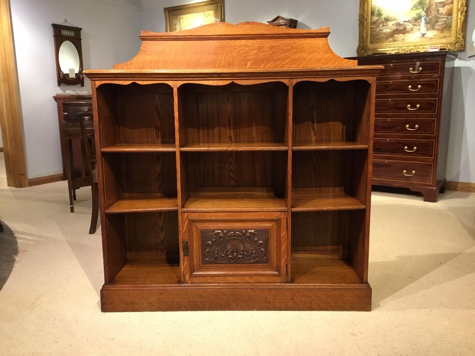 An oak late Victorian period open bookcase. Constructed throughout using the finest quarter sawn oak with beautiful medullary rays. The raised galleried back above a solid rectangular oak top and with five adjustable oak shelves and hinged cupboard