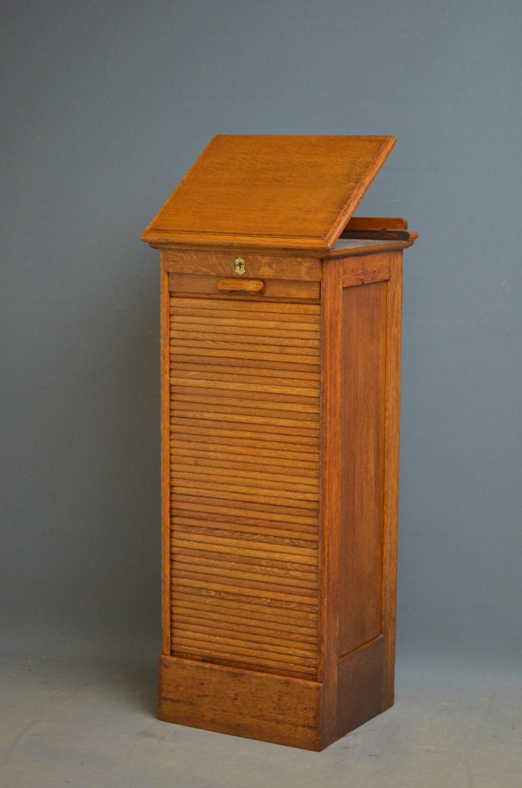 Sn4467, turn of the century oak, tambour fronted filing cabinet of soft color, having molded lift up top and paneled sides above tambour front enclosing 9 drawers, fitted with original working lock and key, standing on plinth base. This antique
