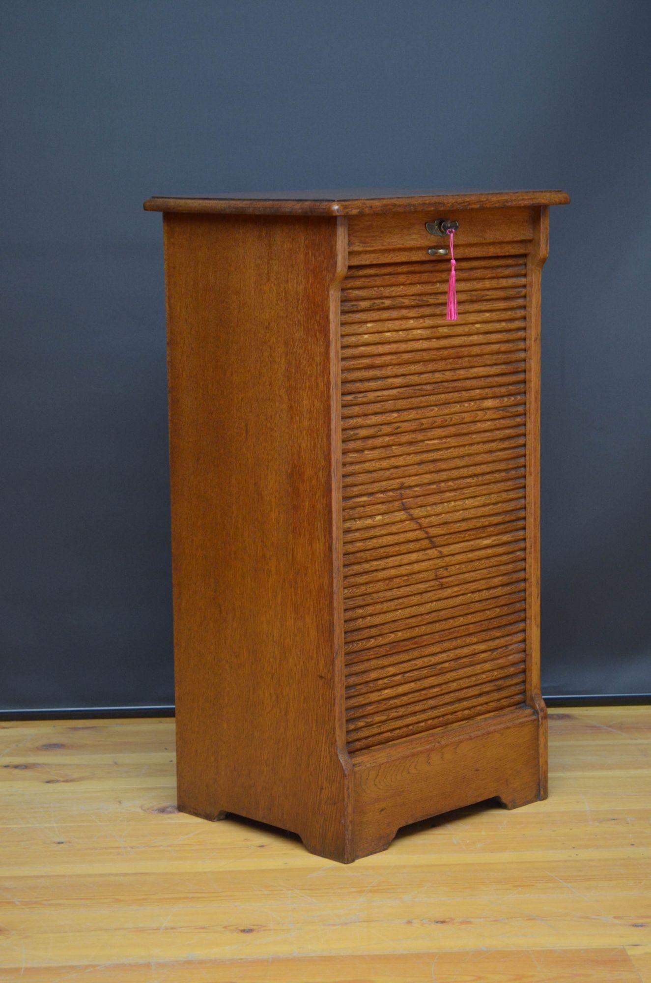 Sn5383 Turn of the century oak, tambour fronted filing cabinet of soft colour, having moulded top and tambour front enclosing 11 sliders, fitted with original working lock and key, standing on plinth base. This antique filing cabinet has been