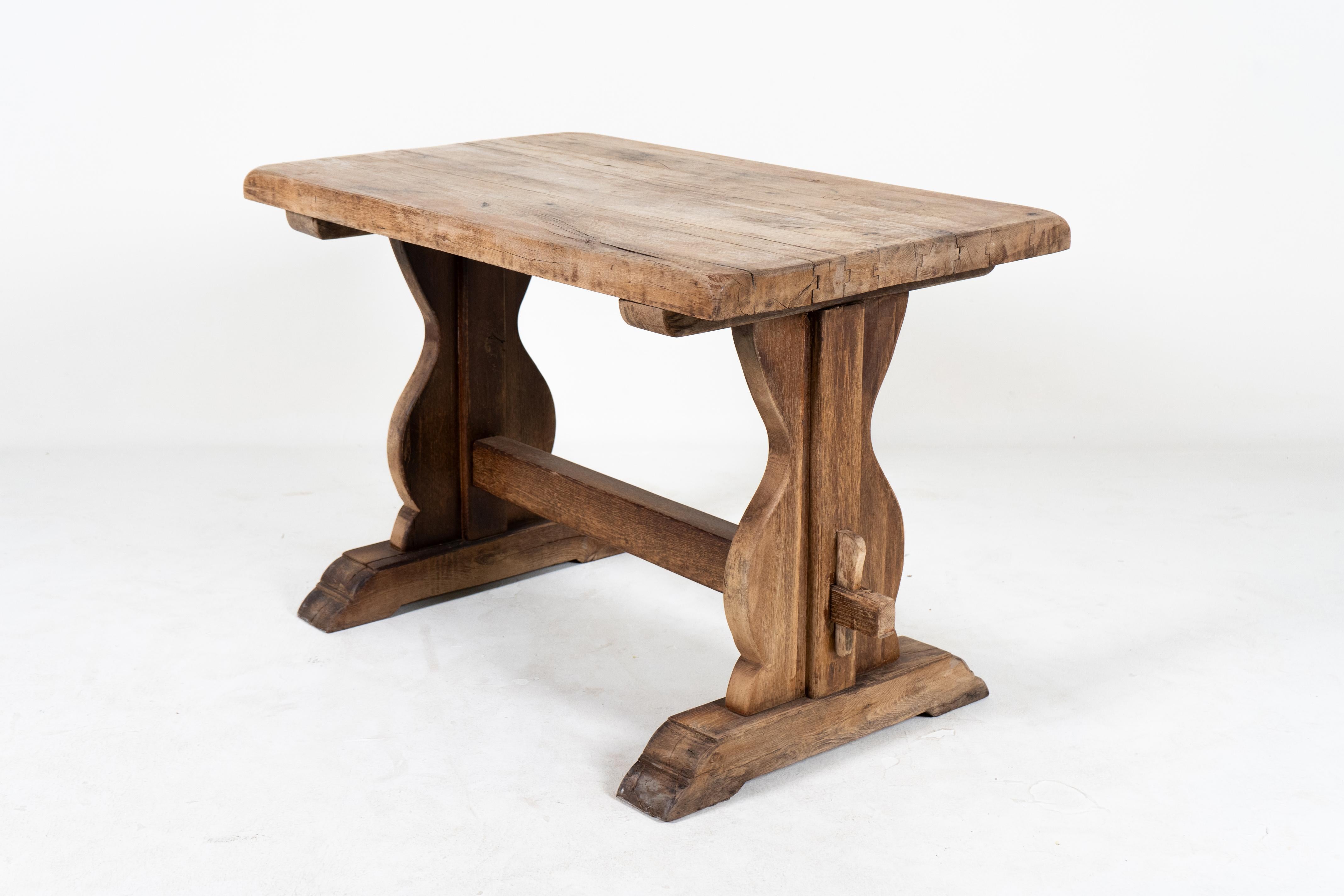 This antique French oak trestle table is unusually study and heavy for its diminutive style.  The original dark varnish has been removed to show the beauty of the underlying wood.  French Oak is relatively free of excessive grain and this table is