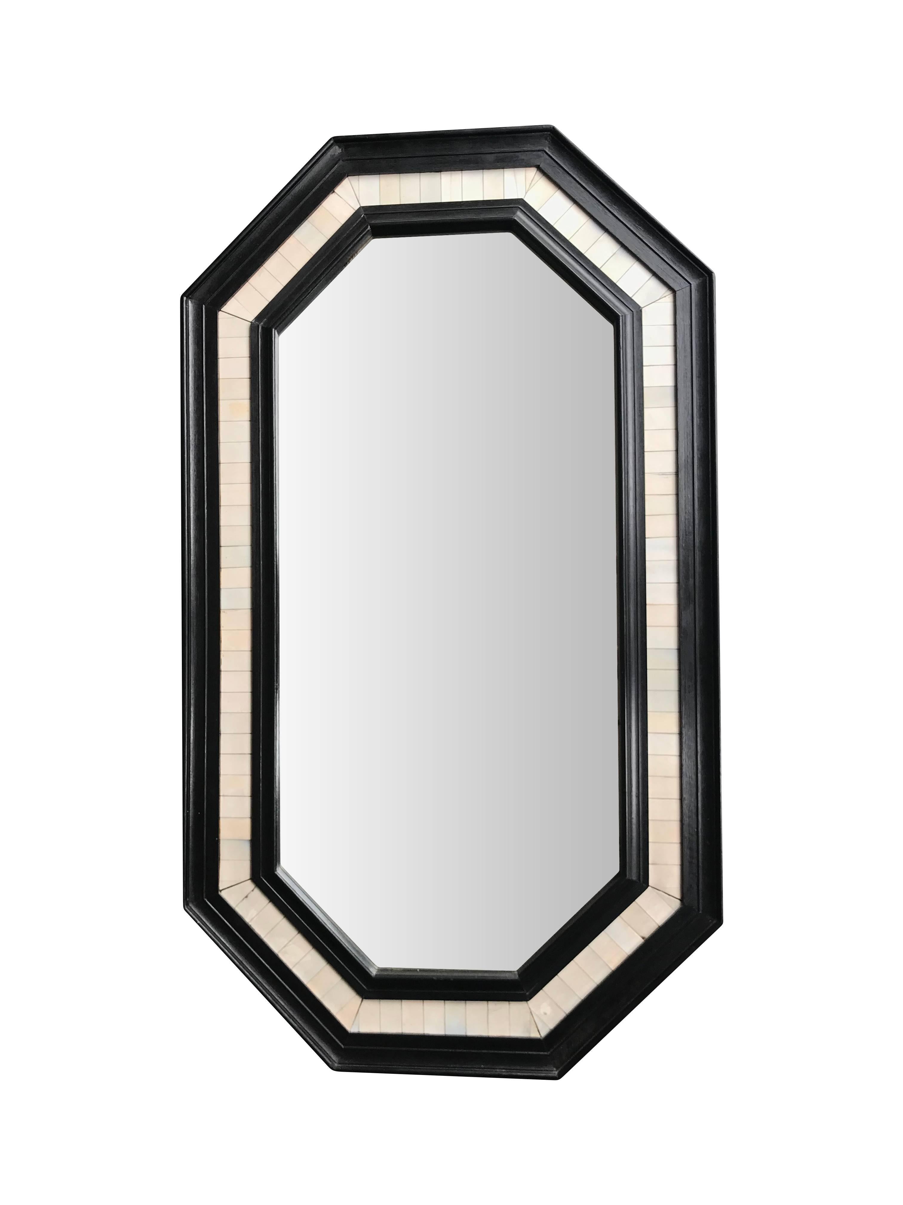 An octagonal ebonized wooden framed mirror with bone inlay surround and bevelled mirror.