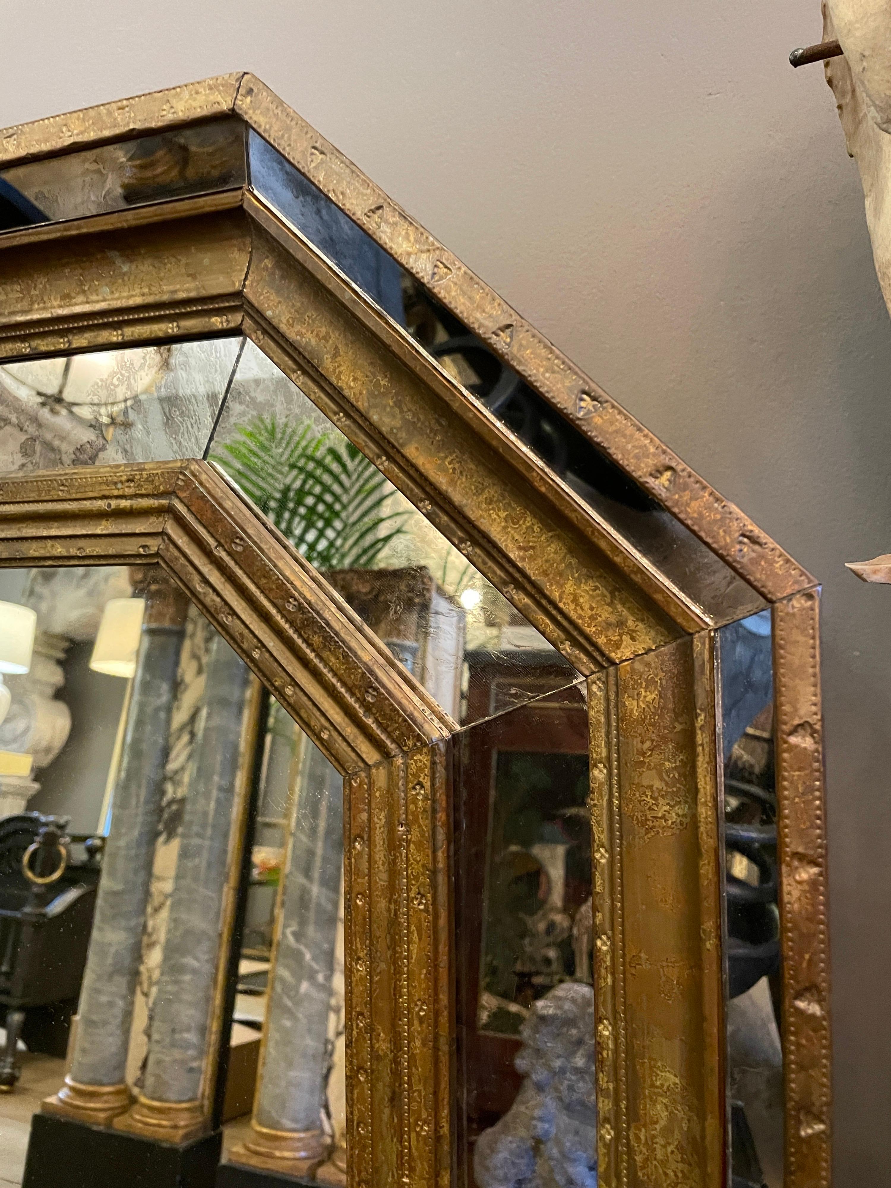 A late 20th century octagonal mirror with a beaten and decorated brass covered frame, the outer mirrored panels with distressed glass. Similar to the Spanish designer R. Dubarry 

French Circa 1970.