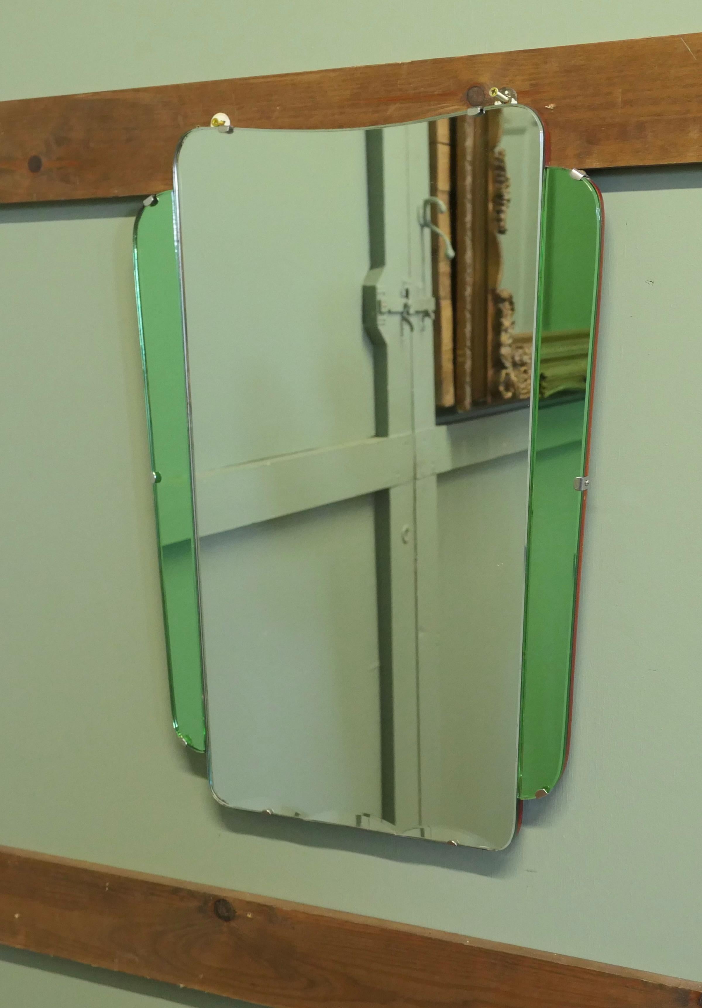 An Odeon Style Art Deco Emerald Wall Mirror.
This is an attractive piece it has a central clear glass mirror with wavy bevelling at the bottom and green panels at both sides
The mirror is in good condition, it is 24” tall, 17.5” wide at the top