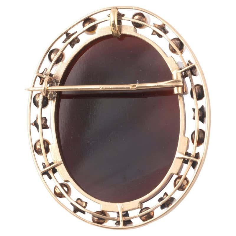 The oval onyx cameo, carved to depict the double portrait in profile, within rose diamond and pearl border, mounted in silver and gold Length 6cm