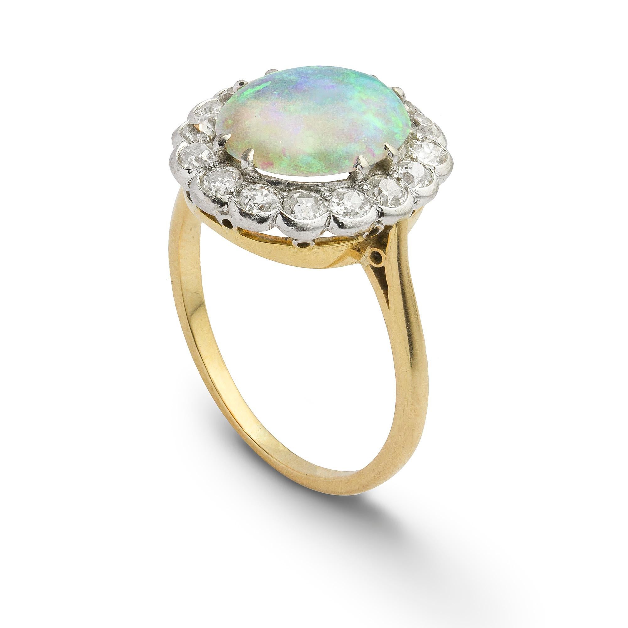 An early 20th century opal and diamond cluster ring, the oval cabochon cut opal measuring approximately 10.7 x 9mm claw set to the centre of an old cut diamond surround, estimated to weigh 0.7 carats in total, in white rub over setting to a yellow