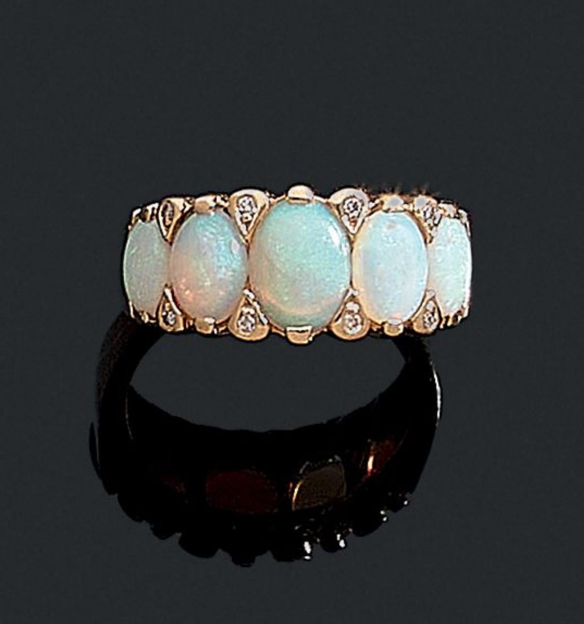 Ring with five opals punctuated at the top and bottom by 8 brilliant cut diamonds. 18K yellow gold frame. French work. Size: 6 3/4. Gross weight: 4.80 gr.