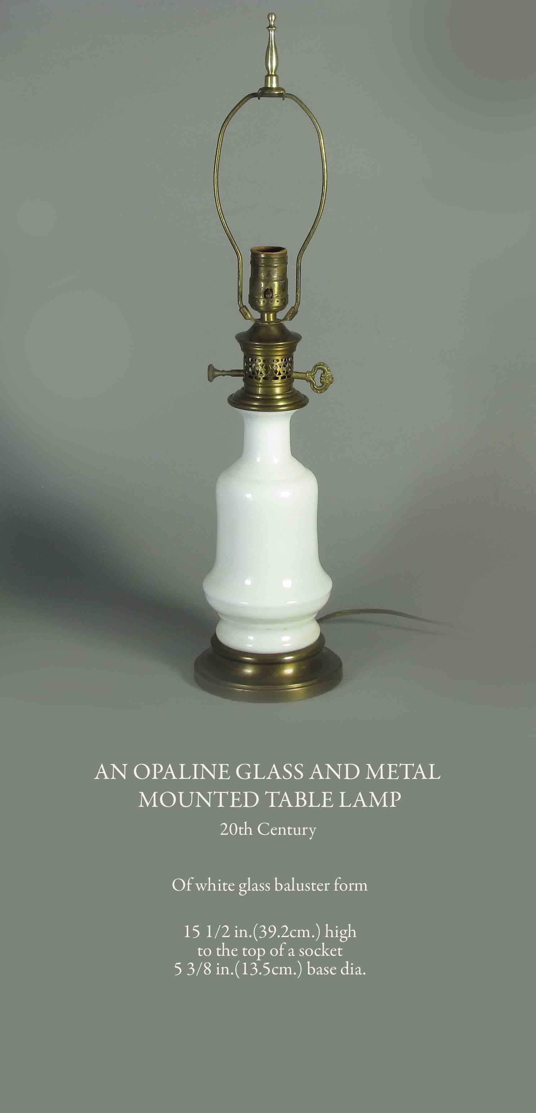 An opaline glass and metal
mounted table lamp
20th Century. 

Of white glass baluster form.

15 1/2 in.(39.2cm.) high
to the top of a socket
5 3/8 in.(13.5cm.) base diameter.