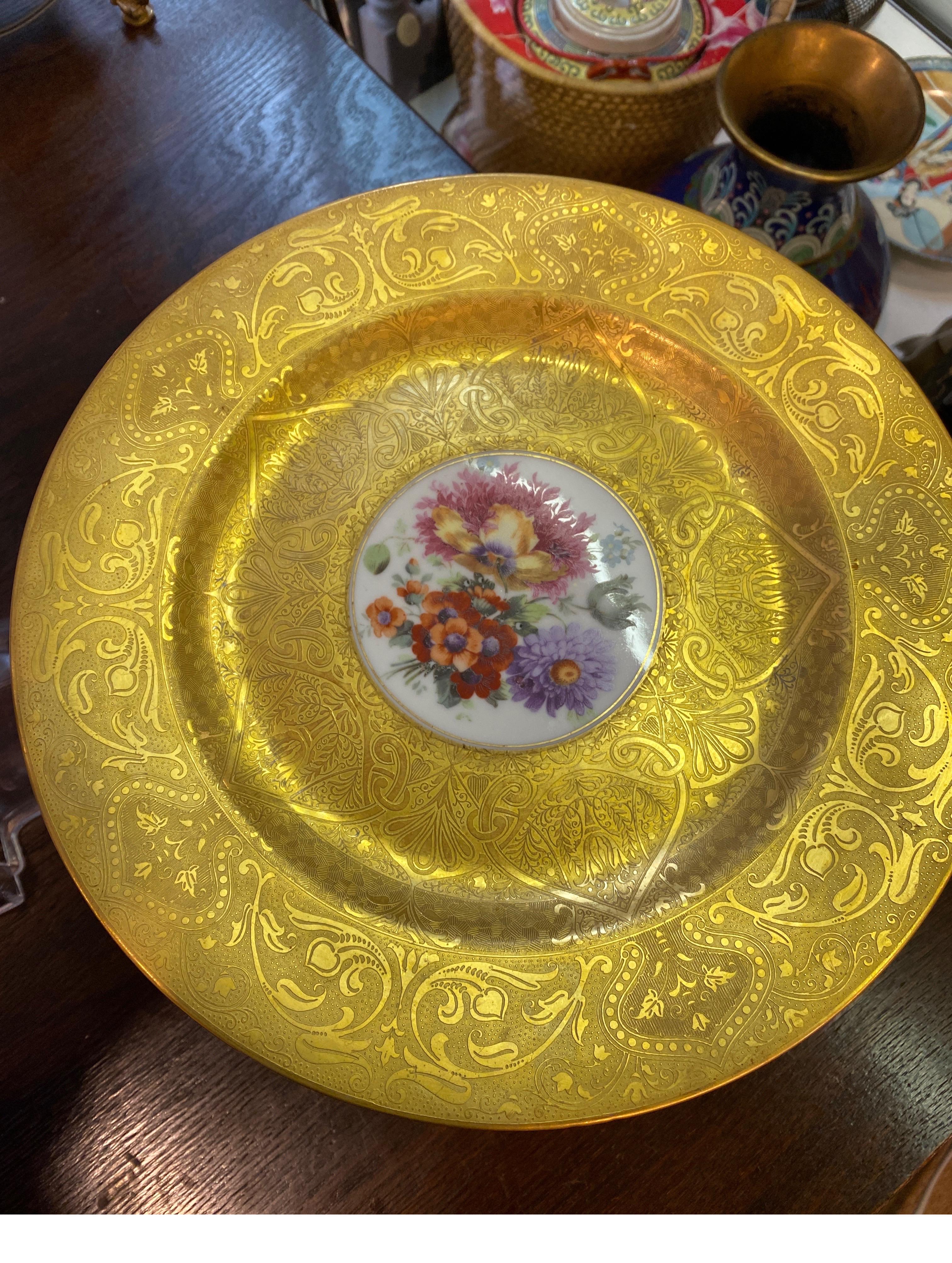 A set of 12 heavy gold encrusted service plates by Hutchenreuther, Germany, Circa 1920's, measuring 10.5 diameter plates with intaglio pattern broad gold borders with central Dresden flower bouquets.  All with blue underglaze mark