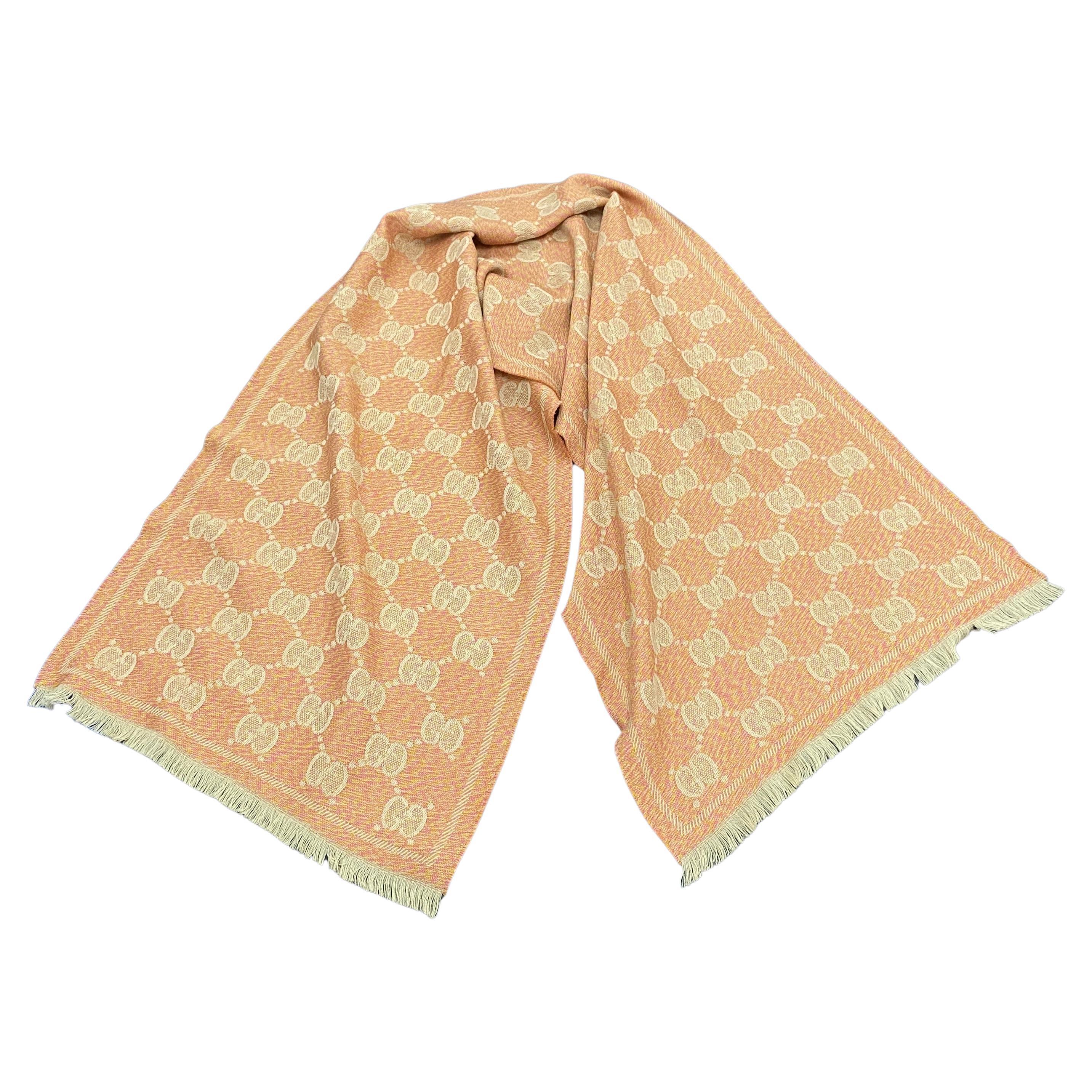 An Orange and Pink Continuous Logo Scarf designed and manufactured in Italy by Gucci, it'is a stylish accessory that combines the iconic Gucci logo with vibrant colors. Gucci is a well-known luxury fashion brand, and their scarves feature their