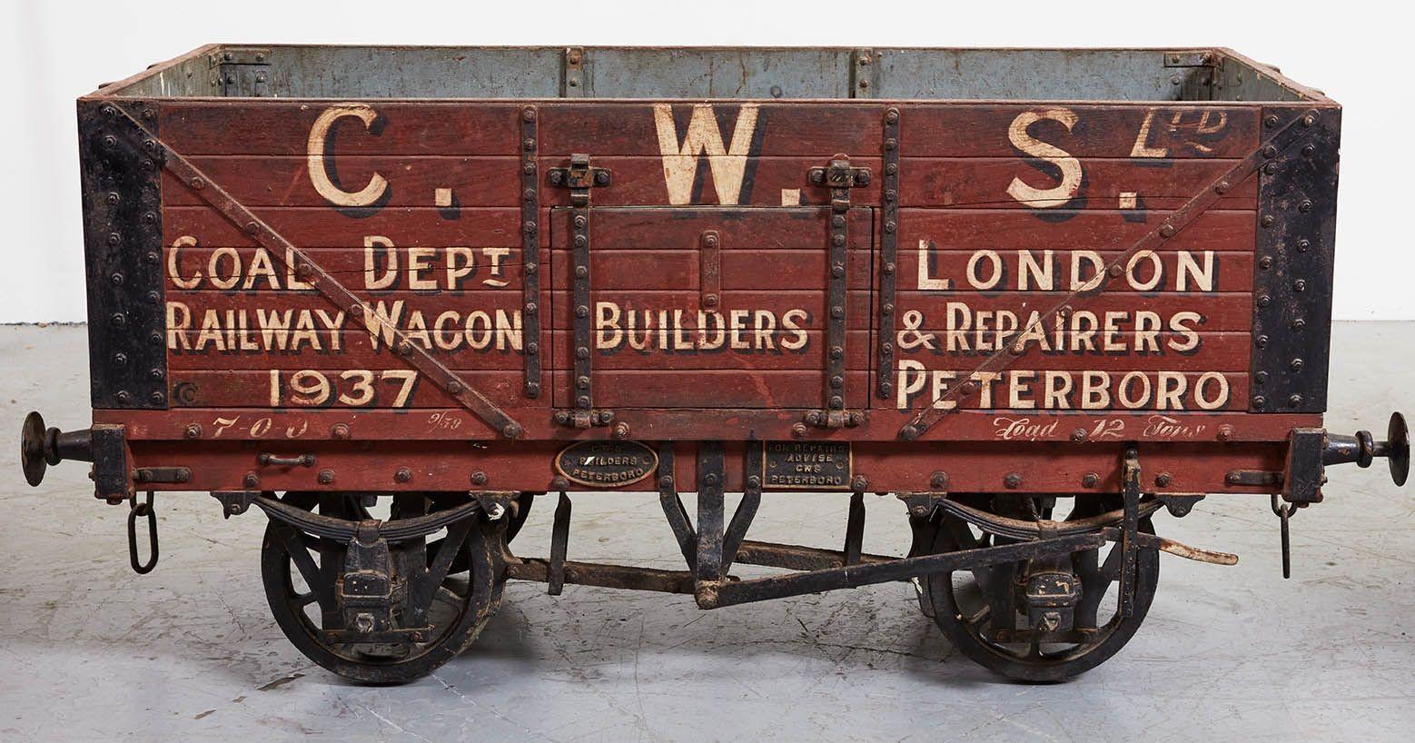 Two fantastic model ore carts on iron wheels and undercarriage in original painted decoration, having riveted iron reinforcing to boarded wooden bodies and with hinged hatch doors to sides, with painted liveries for C.W.S. Ltd, London and