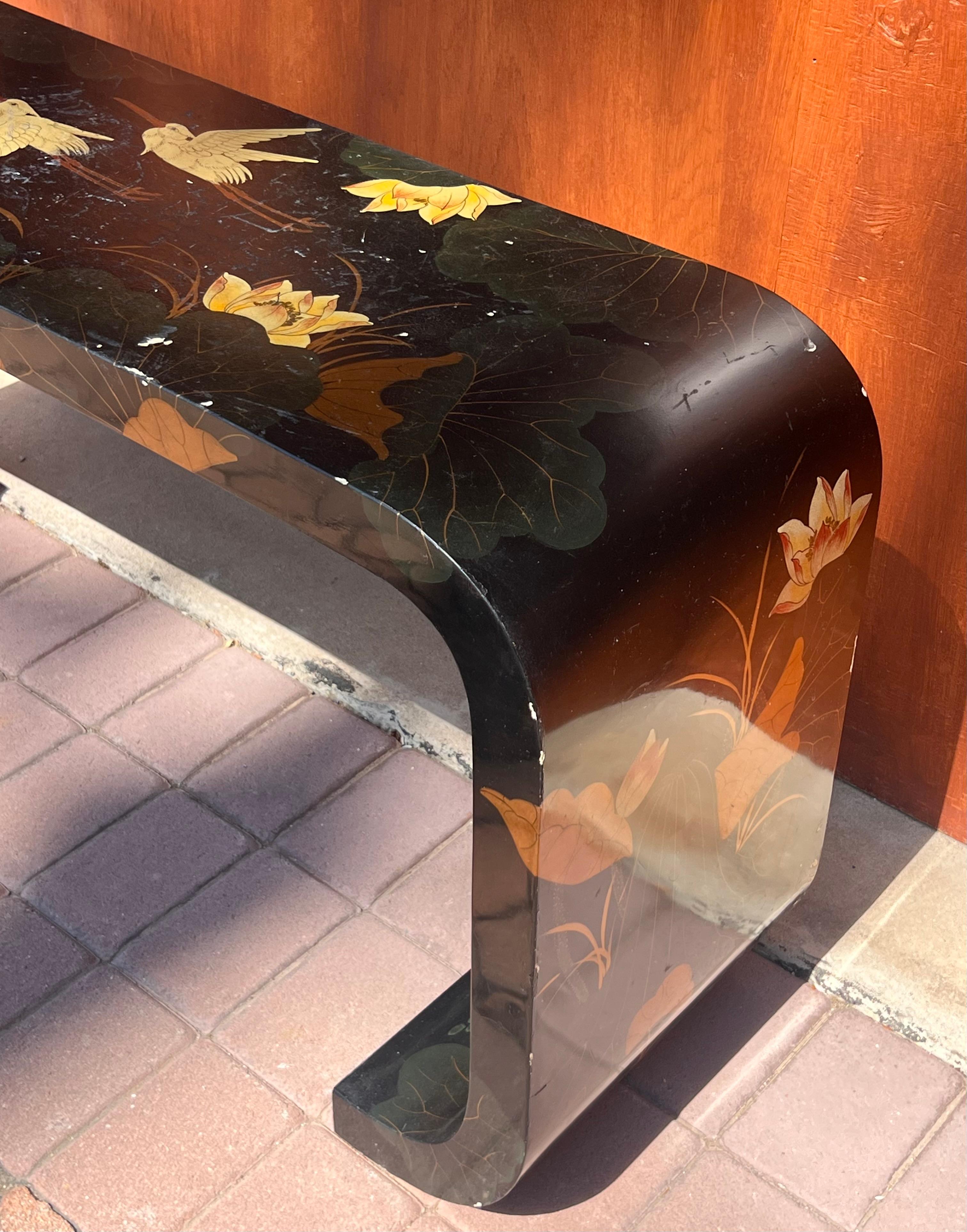 An oriental hand-painted lacquered console, 20th century. Tones of licorice, brick, ochre, and pine, and depicting Asian flora and fauna.
57.25” W x 16.2” D x 27.9” H 