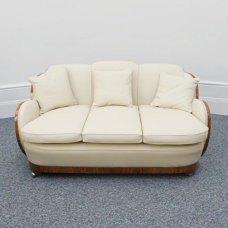 An Art Deco cloud sofa by Harry & Lou Epstein. Three seater cloud back sofa. Burr walnut wrap around veneers and banding. Re-upholstered in cream leather. On polished castors. 

Designer: Harry & Lou Epstein

Dimensions: H 87cm, W 170cm, D 76cm,