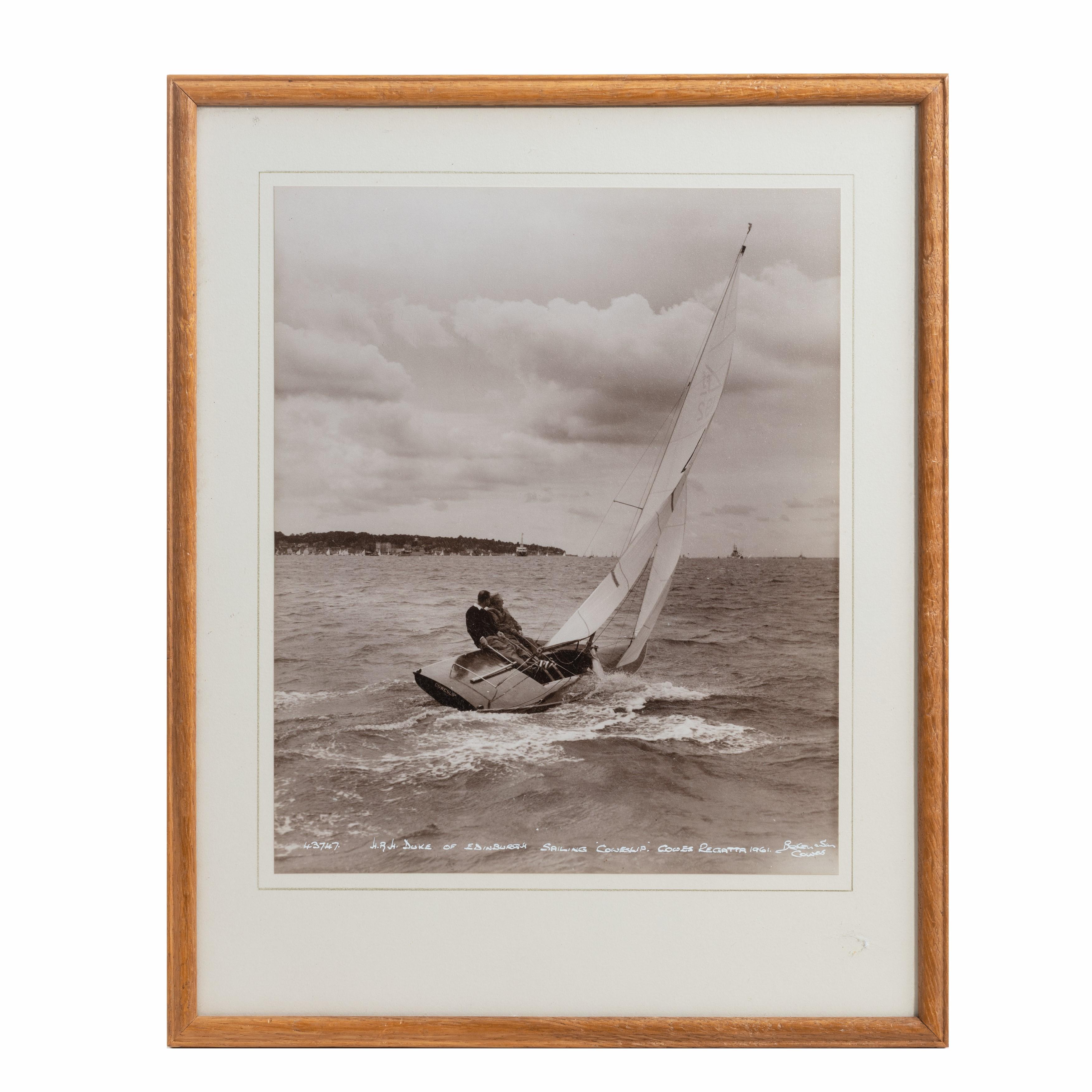 An original Beken photograph of HRH Duke of Edinburgh sailing cowslip, Cowes regatta 1961. In the back ground is the Royal yacht Britannia.
Original oak frame. 

No 43747.
 