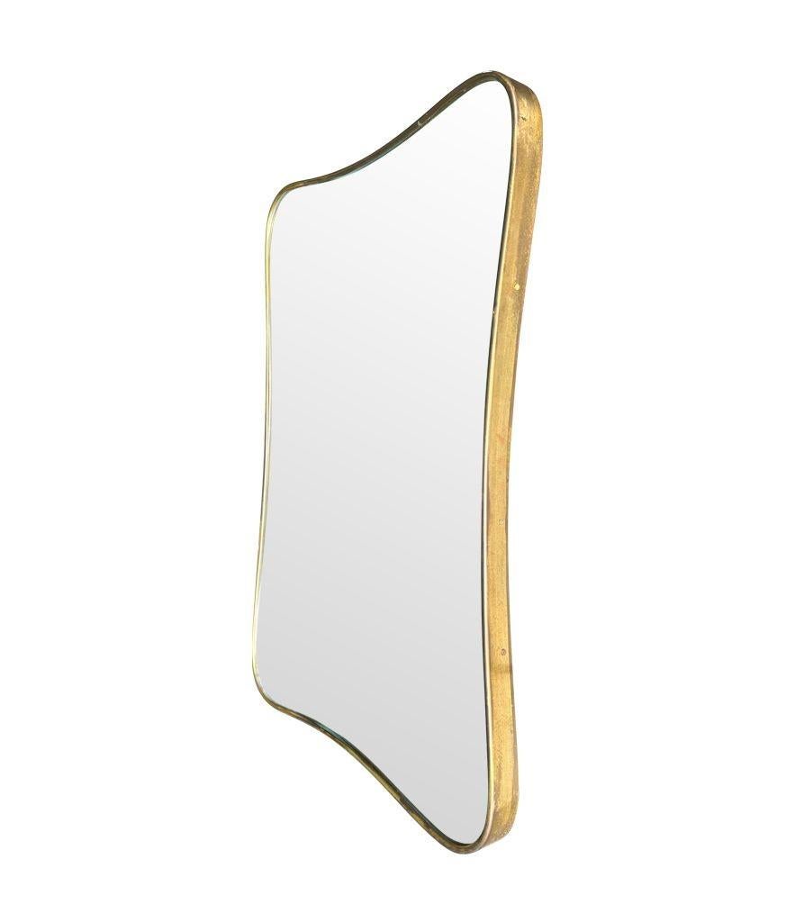 An original Italian 1950s thick brass framed mirror with shaped curved corners, with orignal mirror plate and solid wood back. The mirror is in good condition with some natural patina and tarnish on the brass frame, consistent with age and wear and