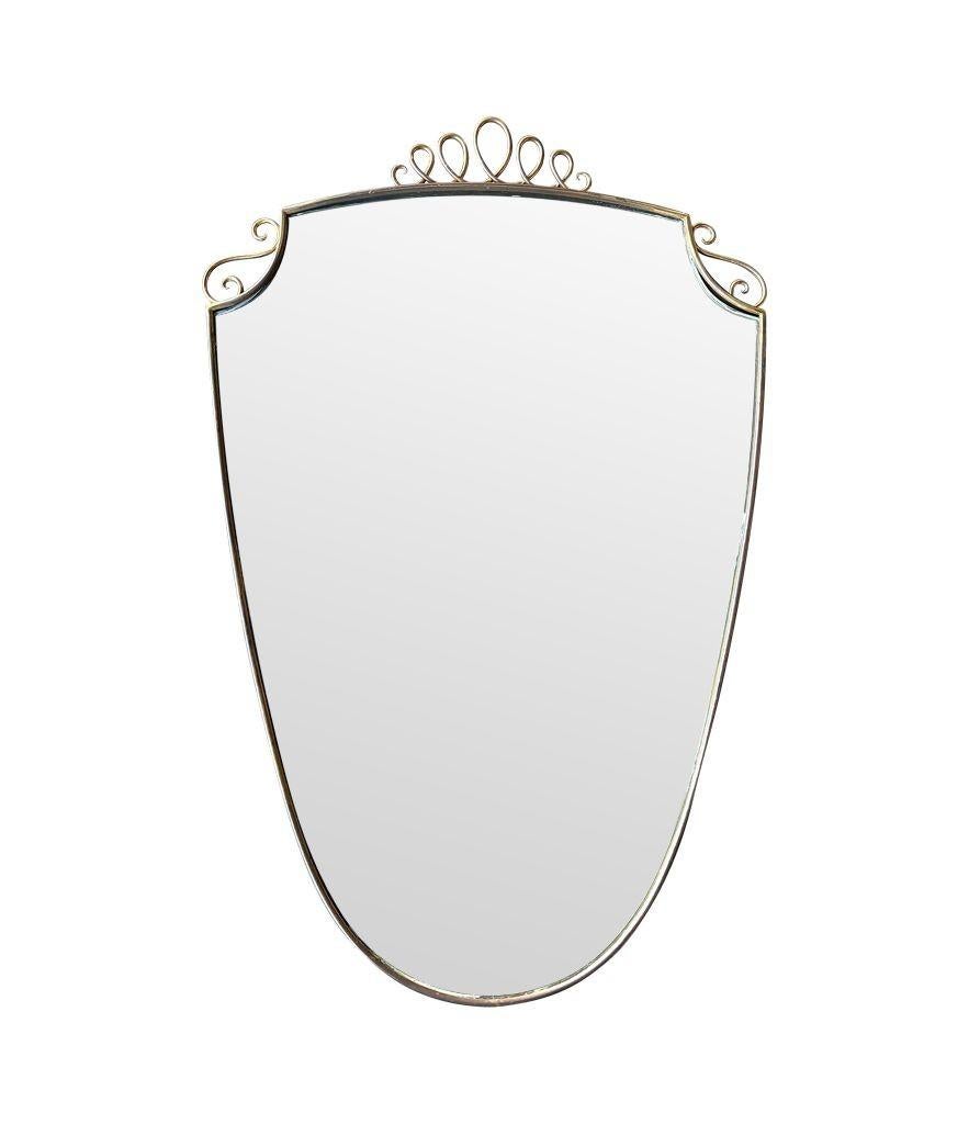 Specchio con cornice in ottone con ritratto in stile Gio Ponti, originale degli anni '50, con dettaglio superiore a volute in ottone, piastra originale e schienale in legno massiccio.