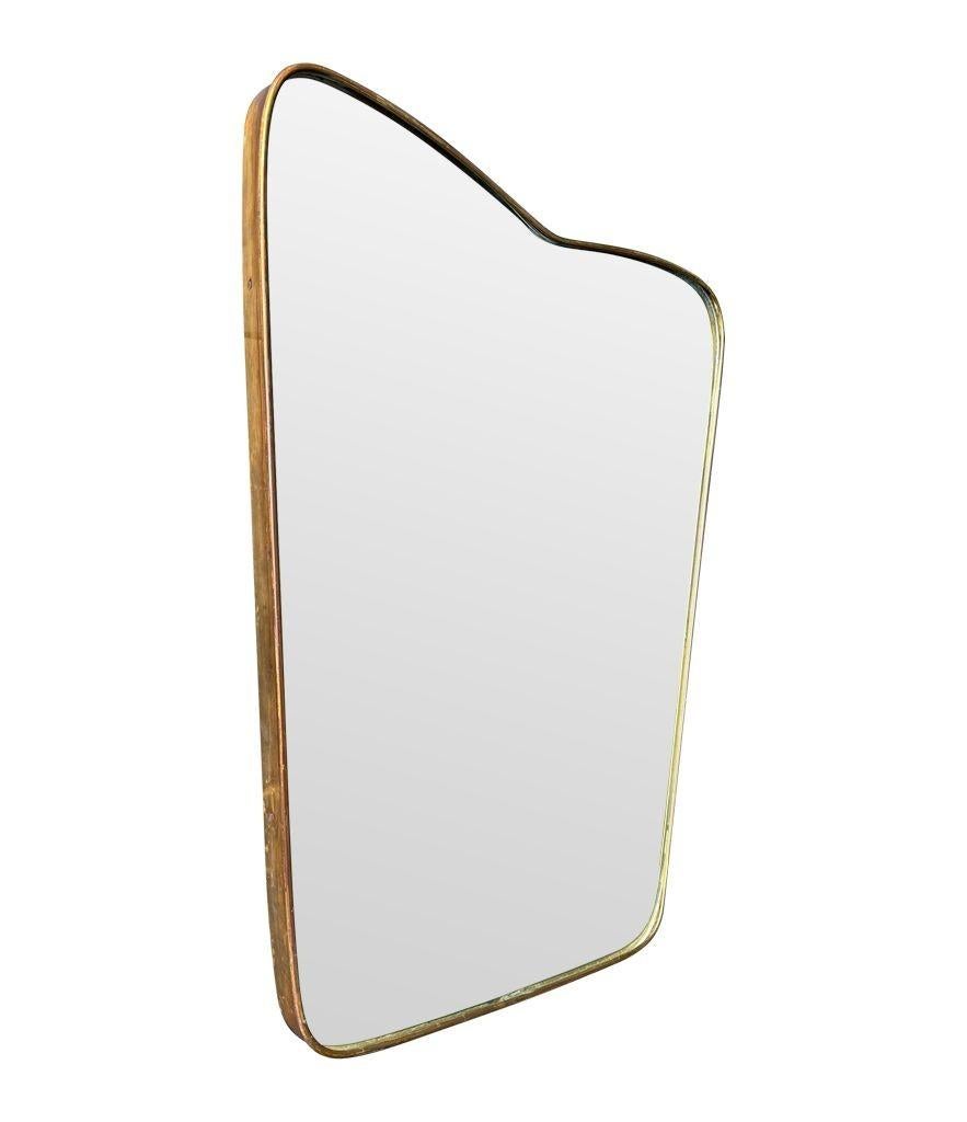 An orignal Italian 1950s mirror with shaped thick brass frame, with orignal mirror plate and solid wood back. There are three small areas of foxing on the back of the mirror plate at the top, but this is totally consistent with mirrors this age. See