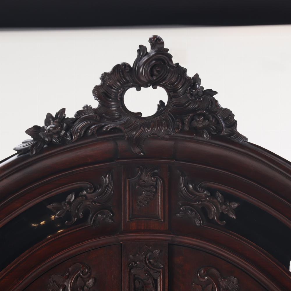 Le plateau arqué est orné d'un bel écusson et d'une frise au-dessus de deux portes vitrées ouvrant sur des étagères en bois. Remarquez les sculptures qui reposent sur le verre, un détail inhabituel et un signe de qualité. 

La base comporte deux