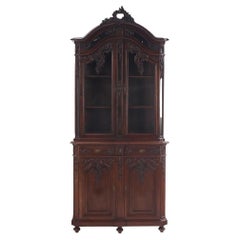 An ornately carved French walnut two-piece vitrine, C 1880, of high quality.