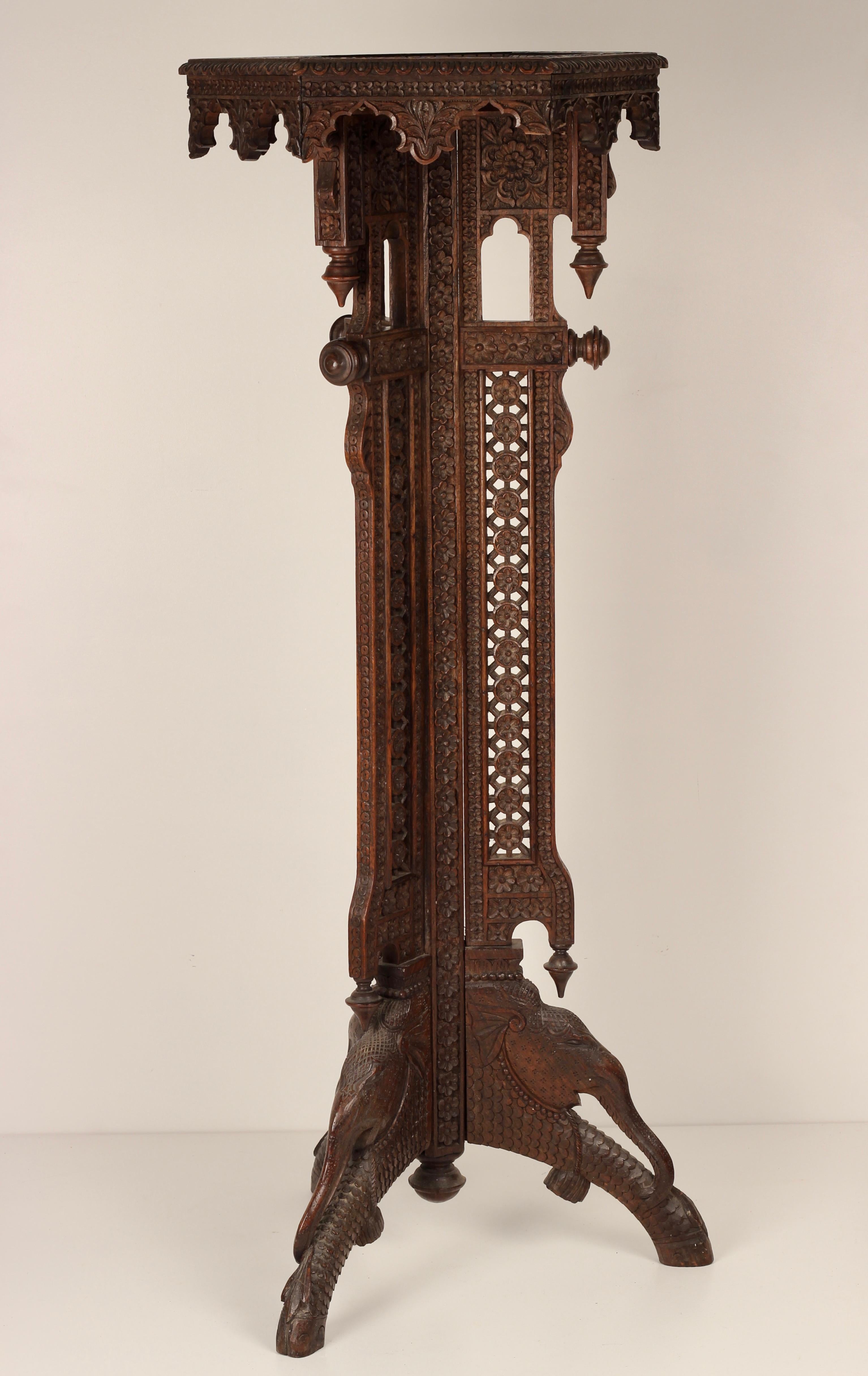 An incredibly detailed an ornate hand carved Torchere from India late 19th Century. Carved into the base of the piece are 4 Elephants shown in profile surrounded by a mass of botanical carved leaves and flower heads. Standing tall and elegant, this