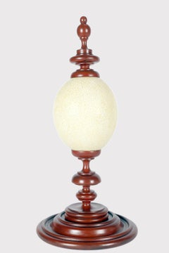 Ein Straußenei aus einer Wunderkammer, mit rot lackiertem Holzsockel, Italien 1900.