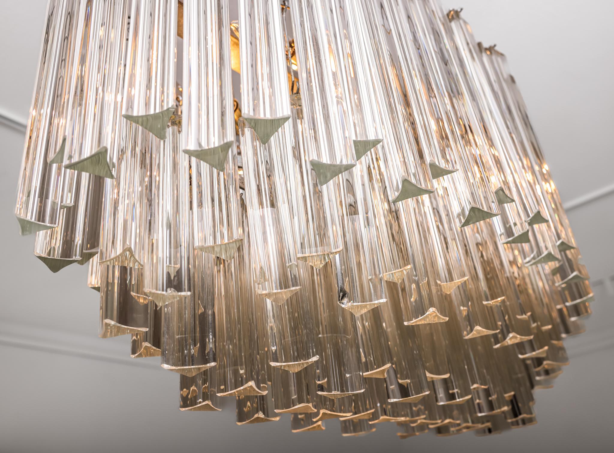 This mid-century chandelier, attributed to Venini, is a complete and sleek three tiered chandelier with transparent Triedri glass prisms. Hung on a two tiered chrome frame with 6