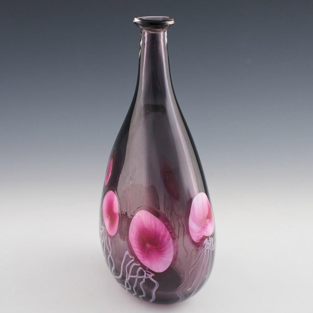 Heading : An Oval Amethyst Jelly Fish Bottle Vase by Siddy Langley
Date : 2023
Origin : Cullompton, Devon
Bowl Features : Tear drop shape. Puce and rose pink jelly fish rising up the vase
Marks : Signed and dated on the base
Type : Lead glass
Size :